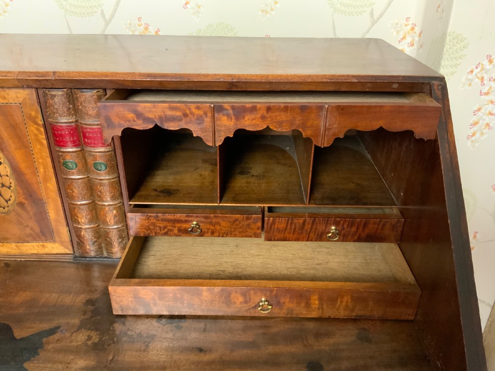A George III mahogany bureau featuring a sloping front flap over four graduated drawers with brass swan-neck handles and bracket feet. View XI