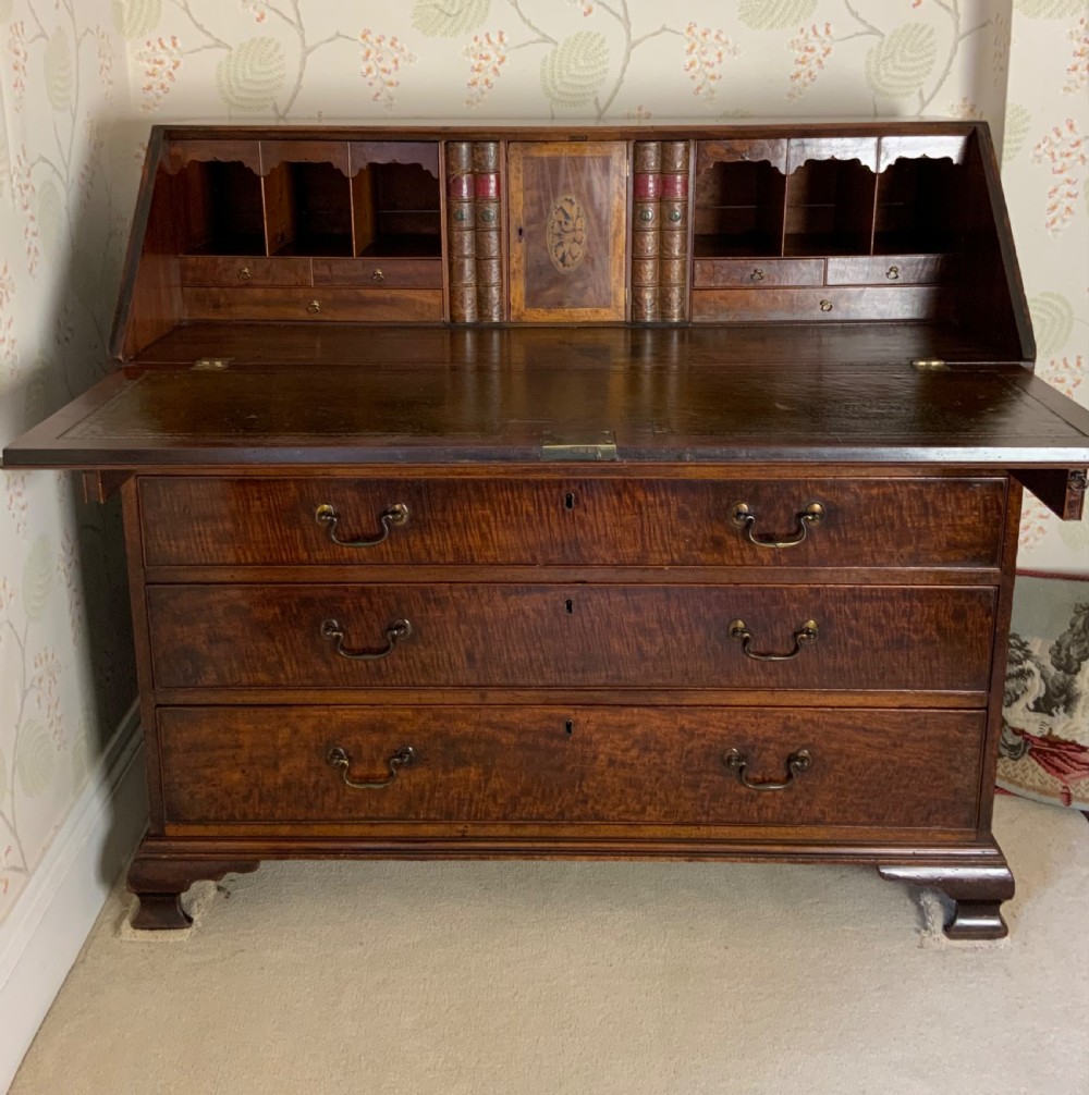A George III mahogany bureau featuring a sloping front flap over four graduated drawers with brass swan-neck handles and bracket feet. View XIII
