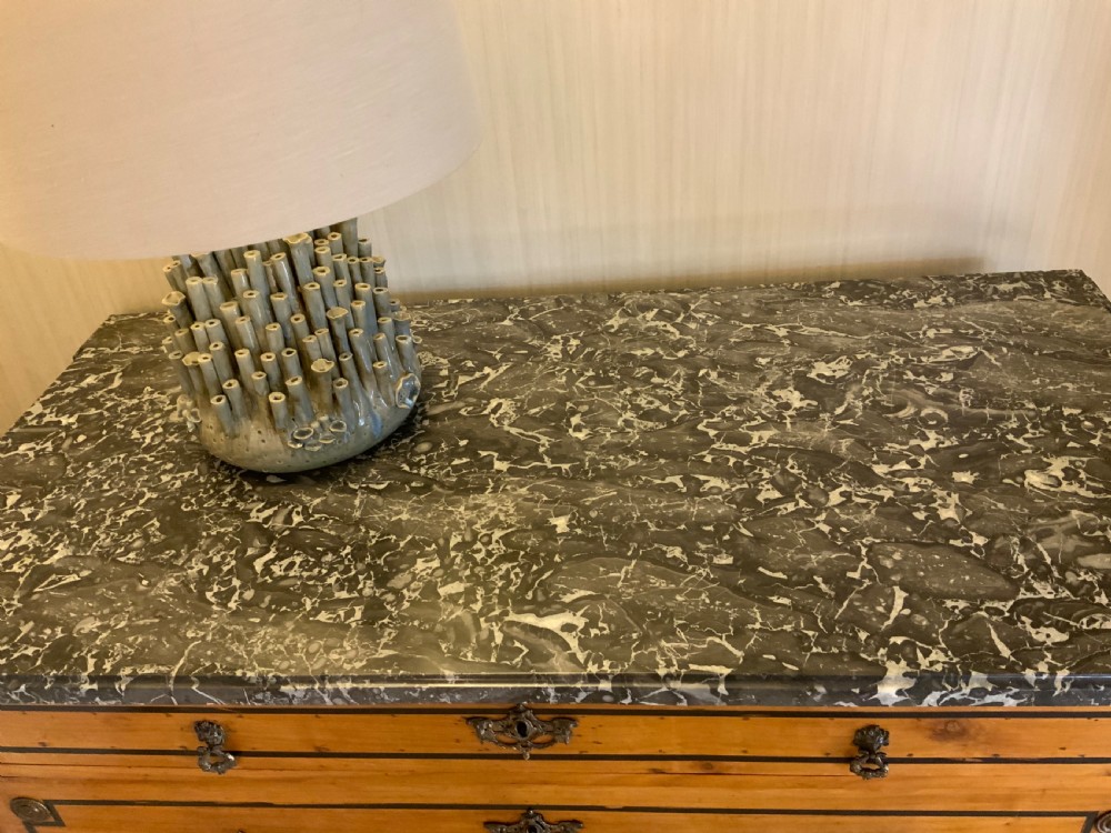 A late 18th-century French Louis XVI style walnut commode featuring three drawers, geometric ebonised inlay, brass hardware, and a dark grey marble top. View IX