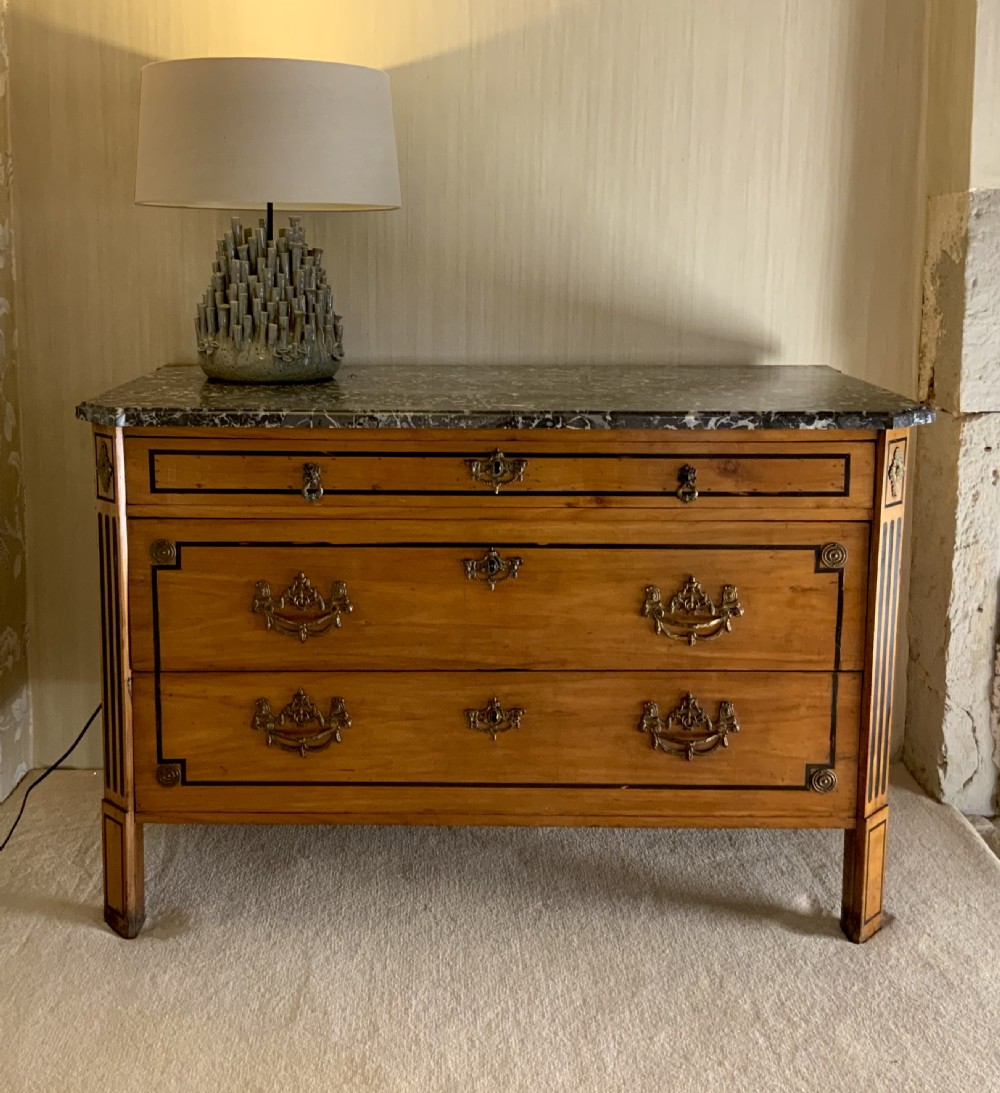 A late 18th-century French Louis XVI style walnut commode featuring three drawers, geometric ebonised inlay, brass hardware, and a dark grey marble top. View XI