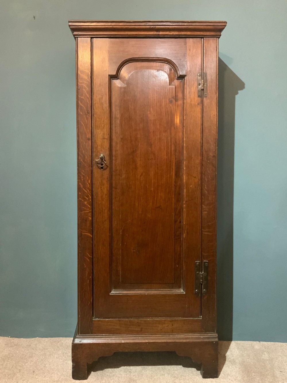 A tall slim, single door oak cabinet