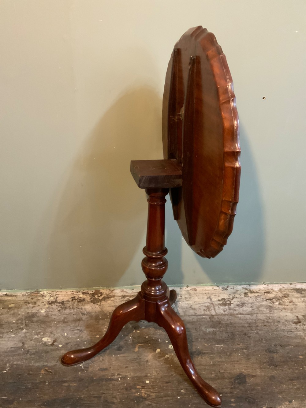 An antique Georgian mahogany tilt-top tripod table with a scalloped piecrust rim, turned central pedestal, and three cabriole legs. View III
