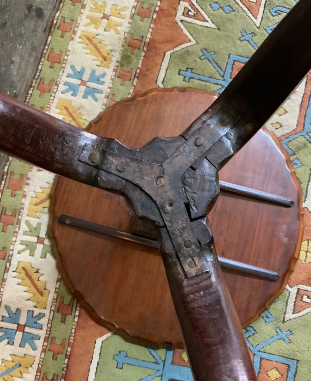 An antique Georgian mahogany tilt-top tripod table with a scalloped piecrust rim, turned central pedestal, and three cabriole legs. View X