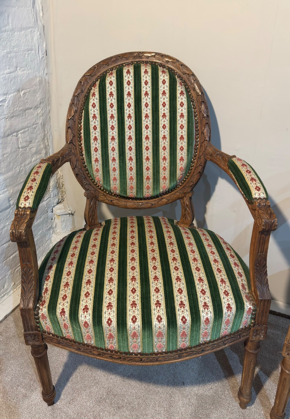 A pair of 19th-century French armchairs featuring carved wooden frames, oval backrests, and green and cream striped fabric upholstery. View III