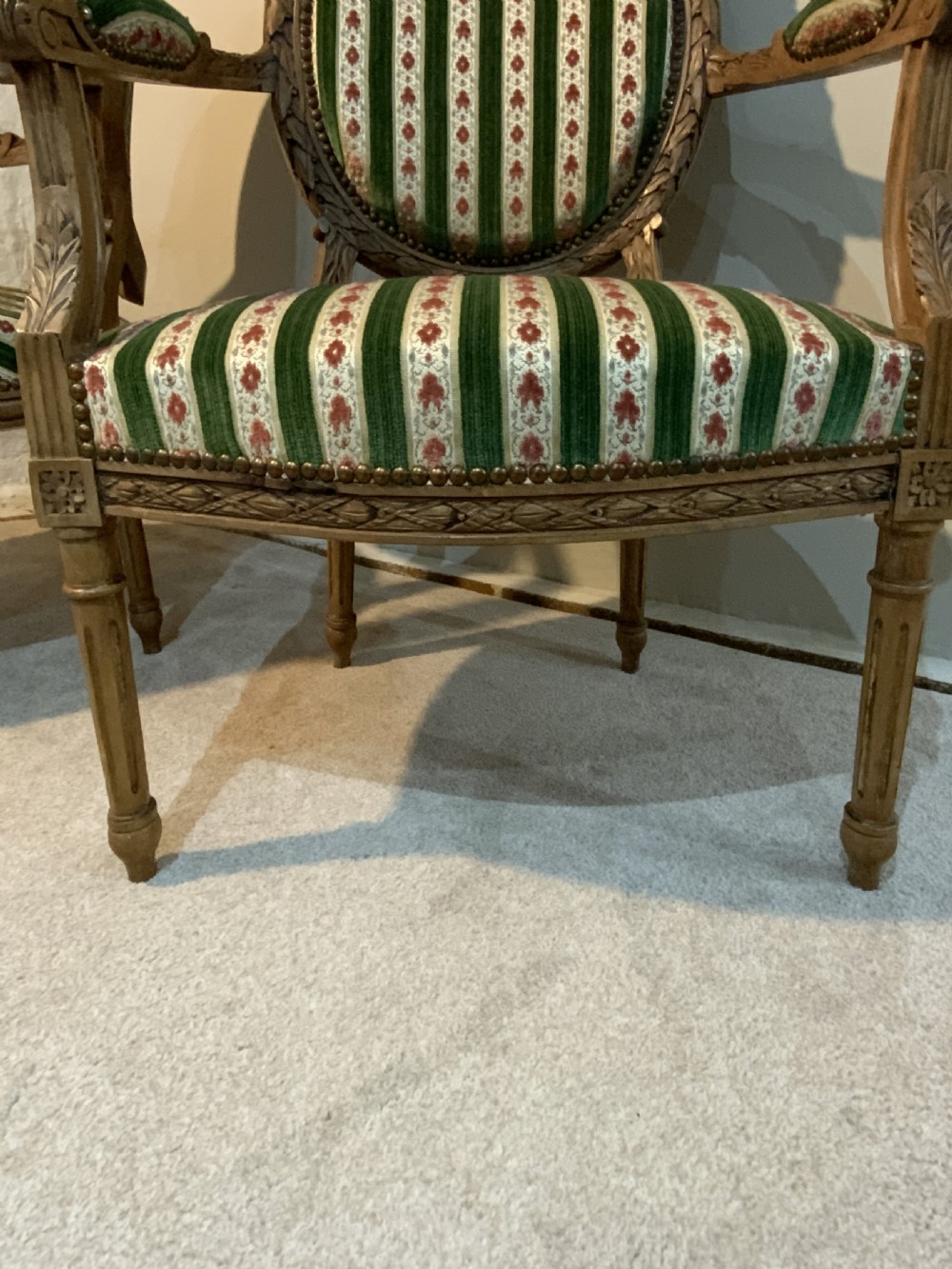 A pair of 19th-century French armchairs featuring carved wooden frames, oval backrests, and green and cream striped fabric upholstery. View VII