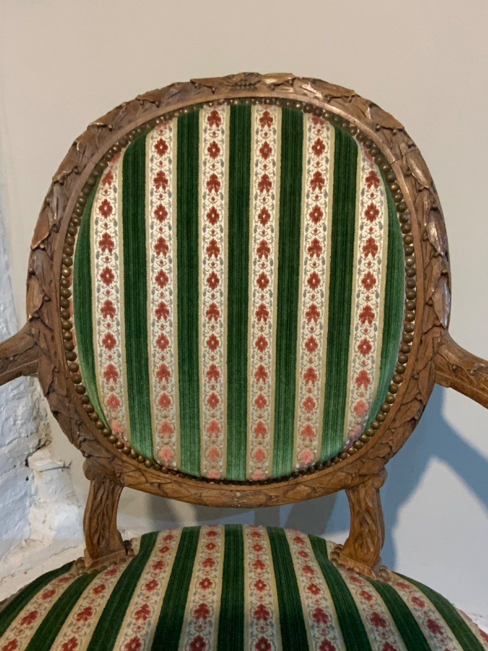 A pair of 19th-century French armchairs featuring carved wooden frames, oval backrests, and green and cream striped fabric upholstery. View IX