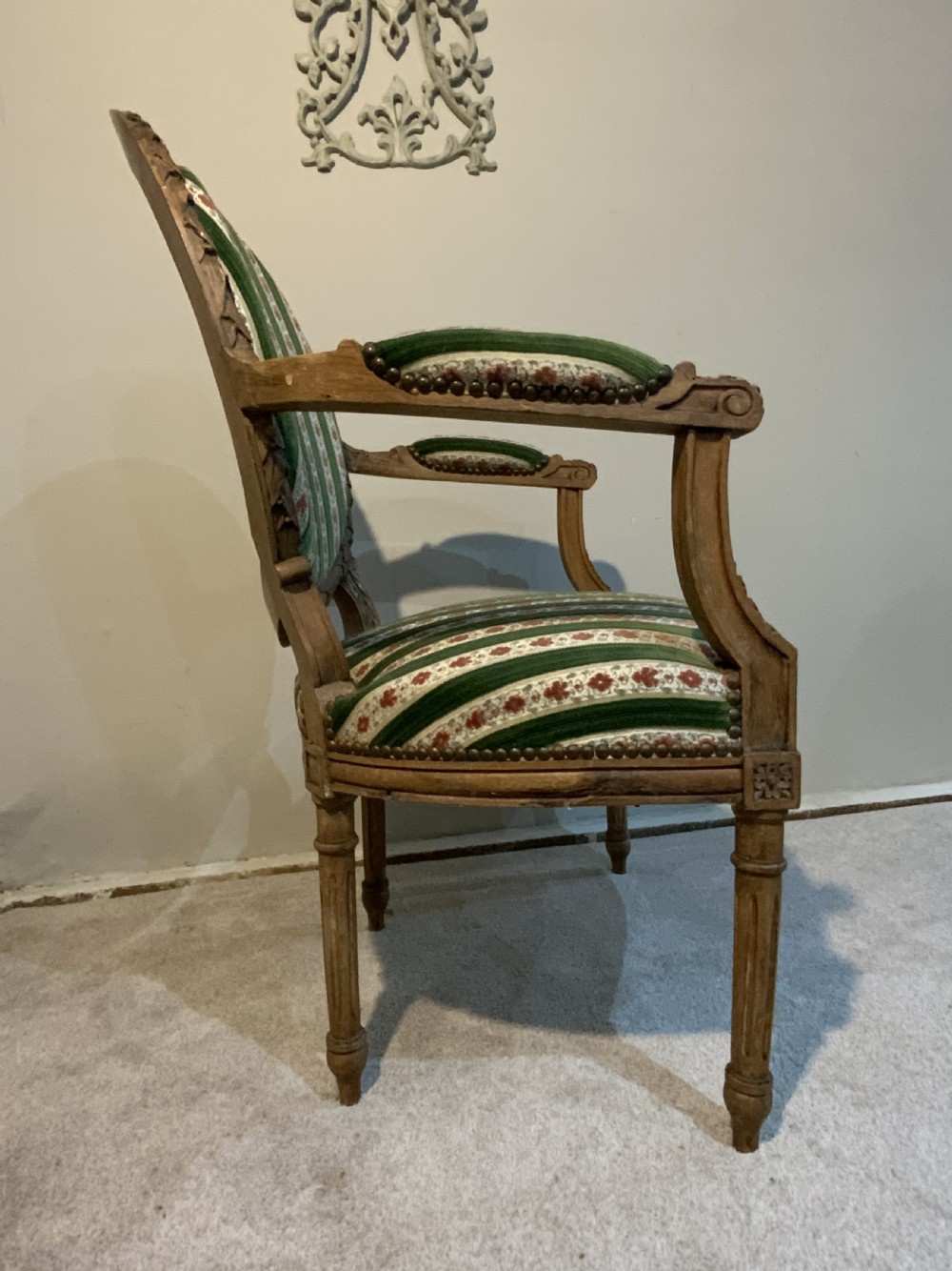 A pair of 19th-century French armchairs featuring carved wooden frames, oval backrests, and green and cream striped fabric upholstery. View XI