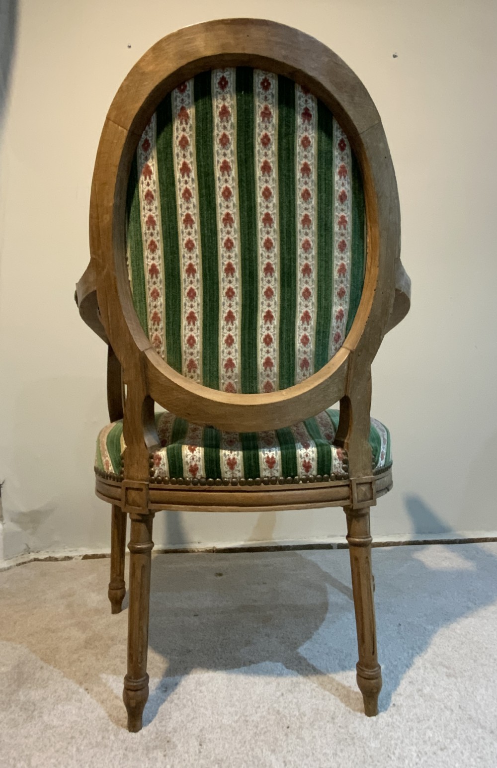 A pair of 19th-century French armchairs featuring carved wooden frames, oval backrests, and green and cream striped fabric upholstery. View XII
