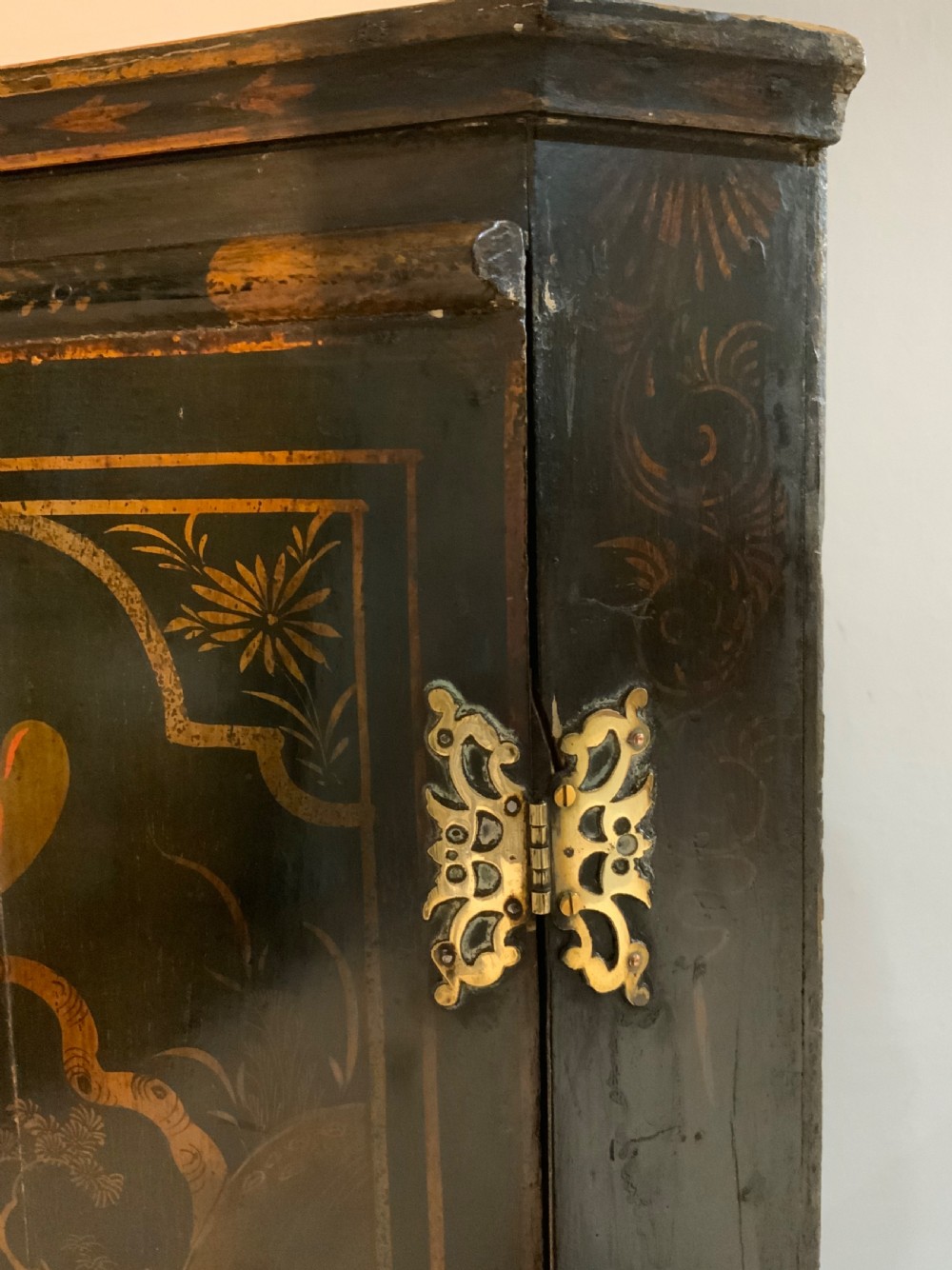 An 18th-century black lacquered corner cabinet featuring gilt chinoiserie artwork of figures, architecture, and a parrot, fitted with decorative brass hinges. View II