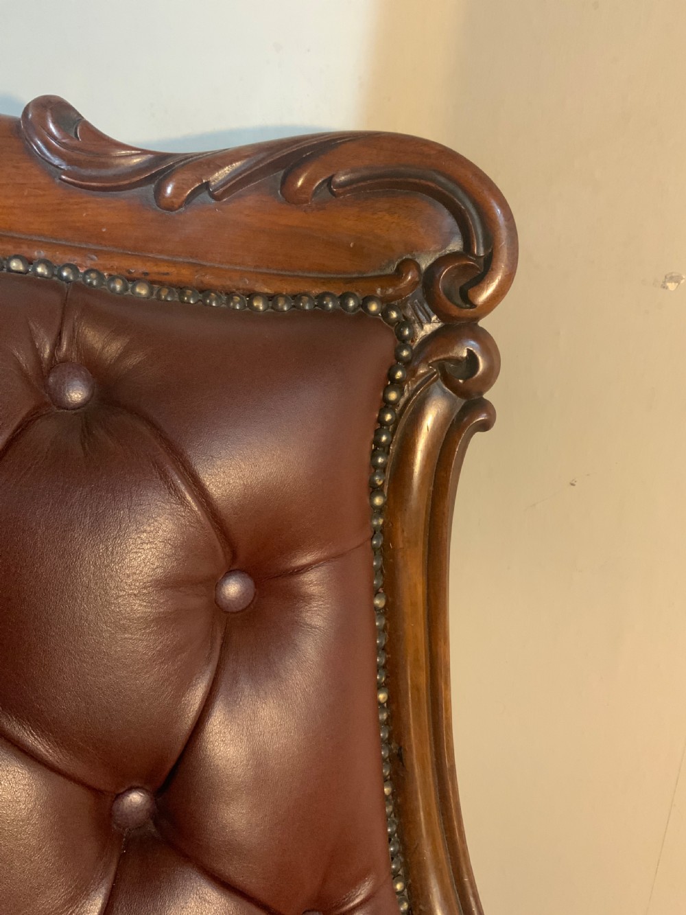 A William IV mahogany library armchair upholstered in button-back burgundy leather with an extending footrest and carved scroll arms. View II
