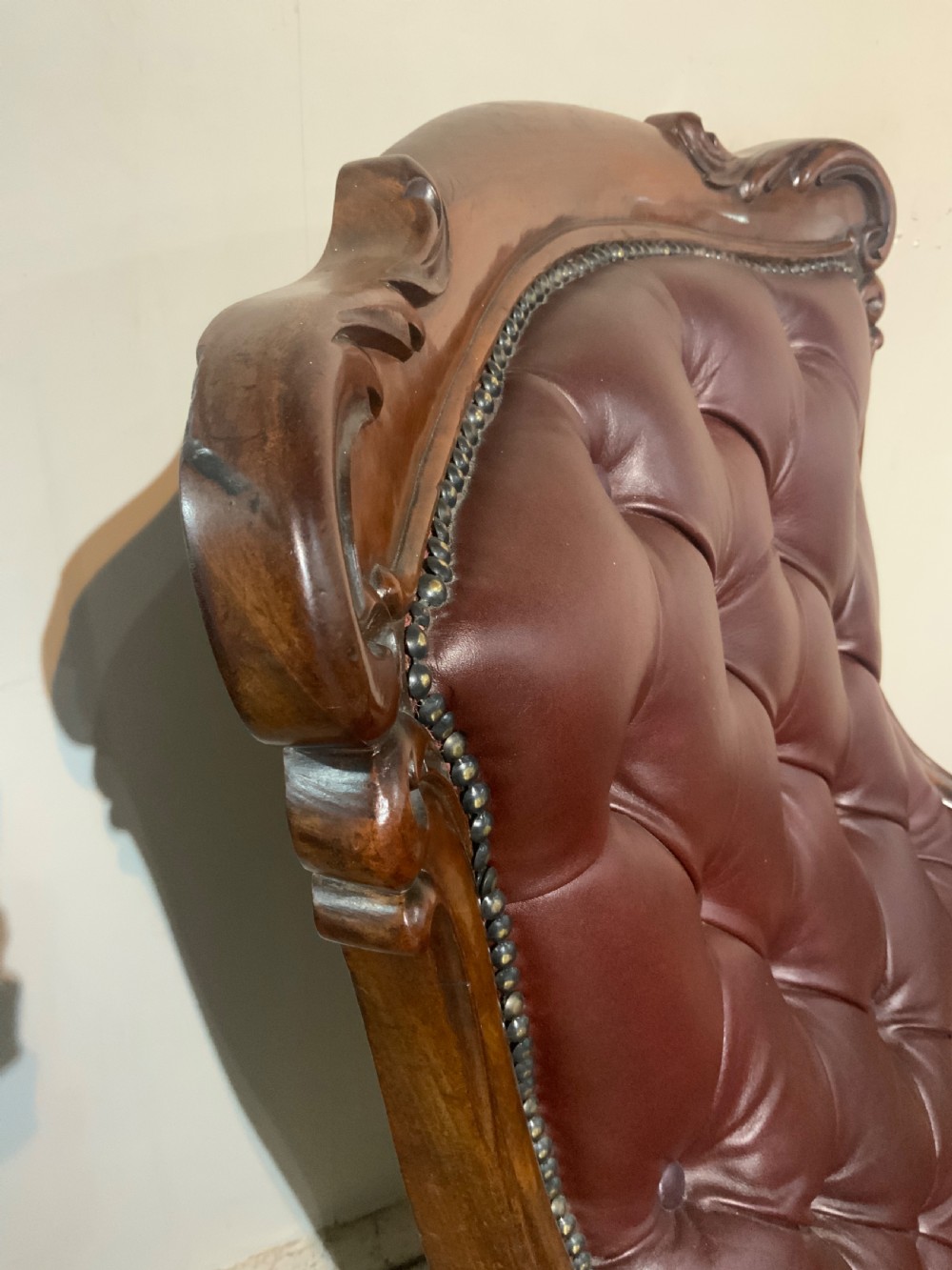 A William IV mahogany library armchair upholstered in button-back burgundy leather with an extending footrest and carved scroll arms. View IV