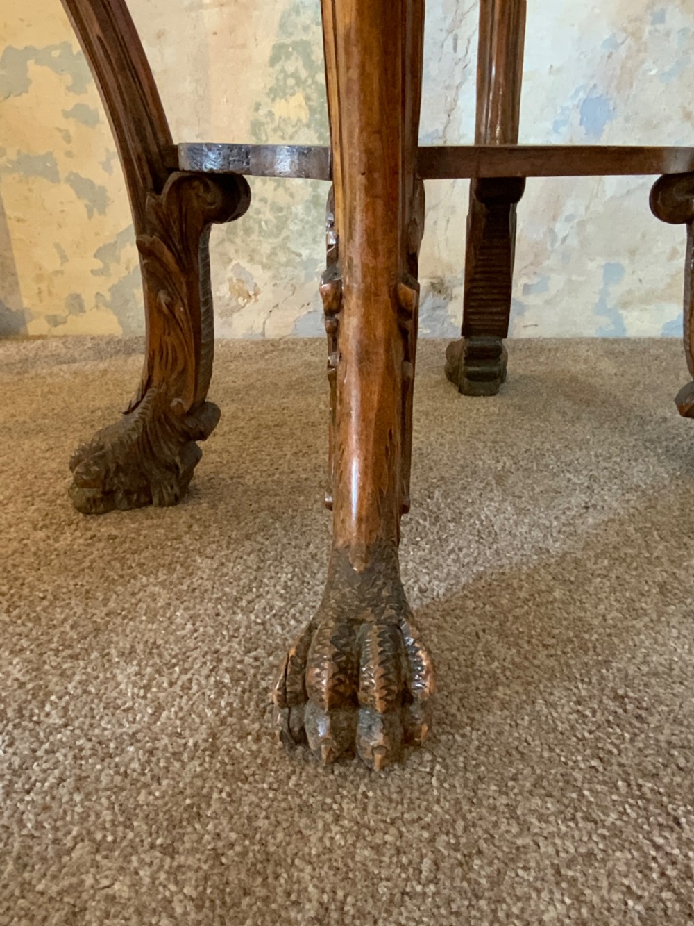 A carved Italian walnut three-legged occasional table featuring sculptural legs shaped like mythical figures terminating in claw feet with a lower undertier shelf. View II