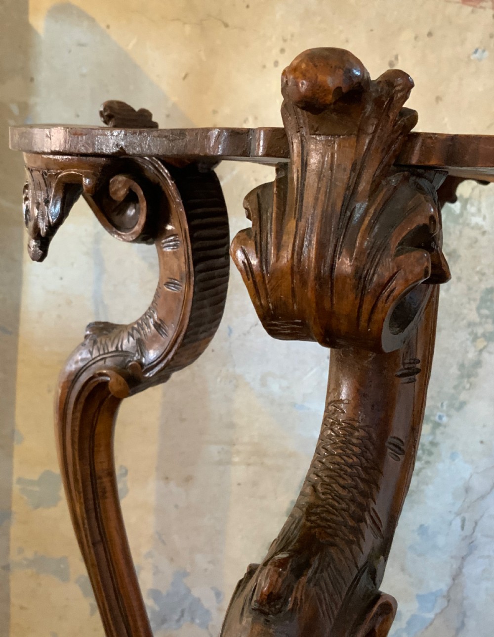 A carved Italian walnut three-legged occasional table featuring sculptural legs shaped like mythical figures terminating in claw feet with a lower undertier shelf. View III