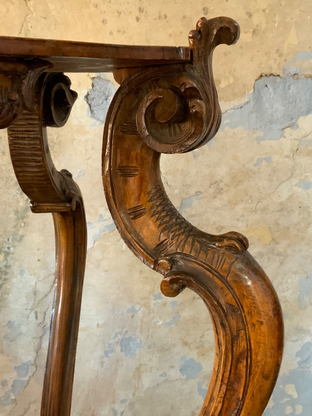 A carved Italian walnut three-legged occasional table featuring sculptural legs shaped like mythical figures terminating in claw feet with a lower undertier shelf. View V