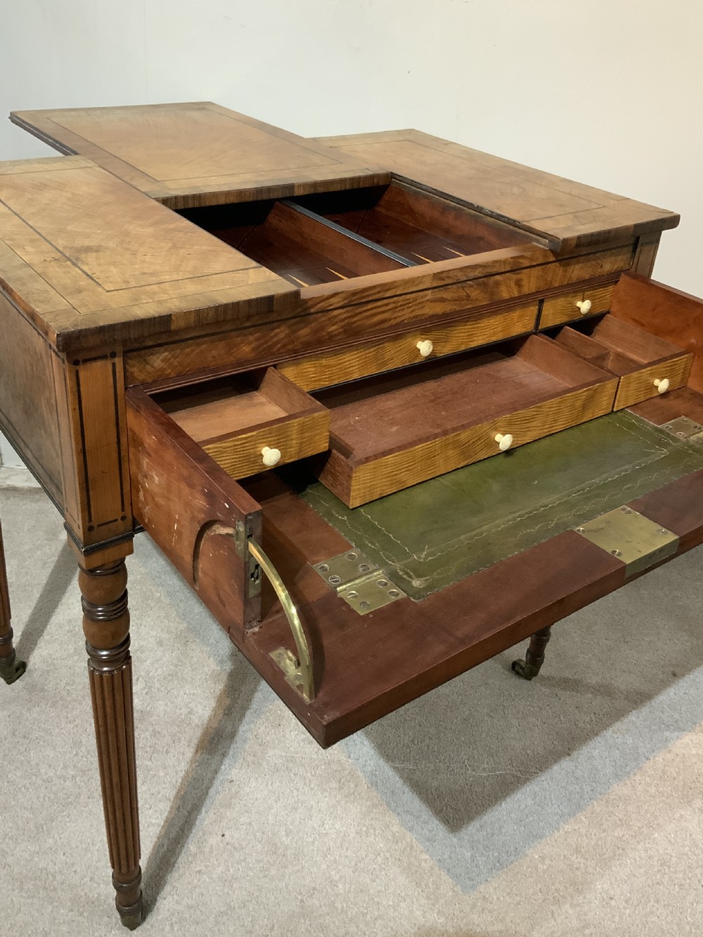 An antique mahogany Regency games and writing table featuring reeded legs, brass handles, a pull-out drawer with a green leather insert, and a reversible top revealing a game board compartment. View III