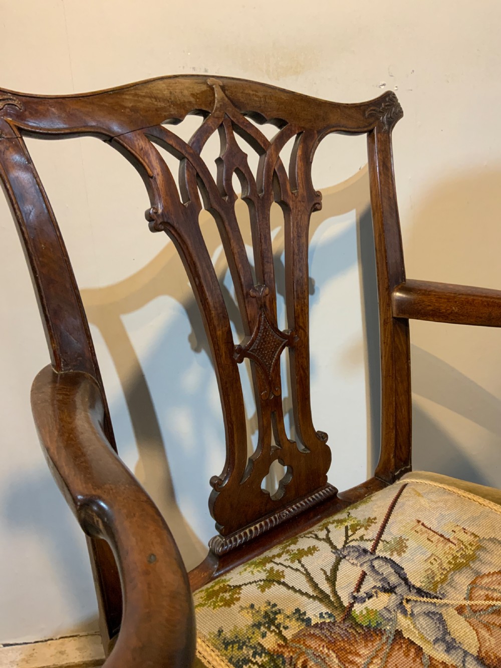 A Georgian dark mahogany armchair featuring an intricately carved pierced back splat, open curved arms, and a green velvet seat with an embroidered tapestry panel. View IV