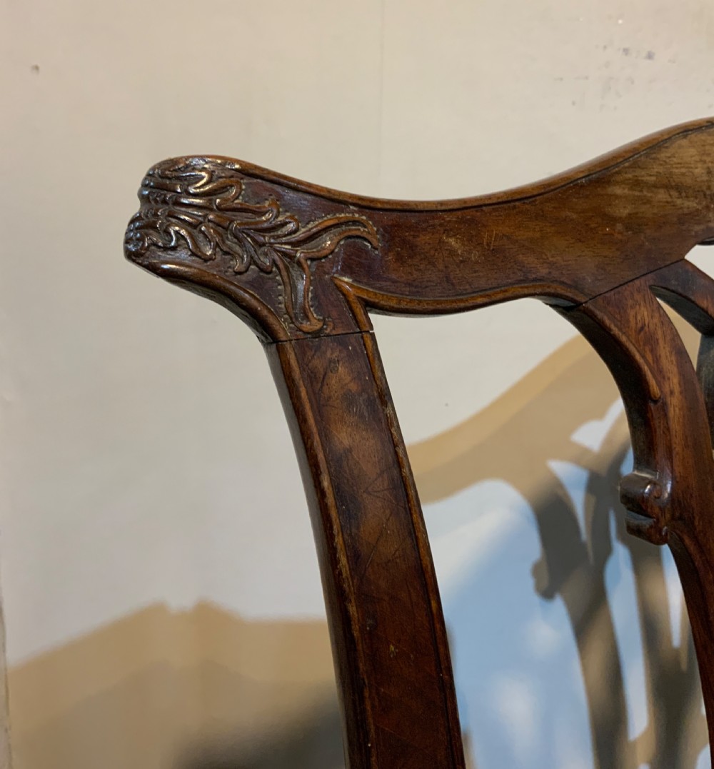 A Georgian dark mahogany armchair featuring an intricately carved pierced back splat, open curved arms, and a green velvet seat with an embroidered tapestry panel. View V