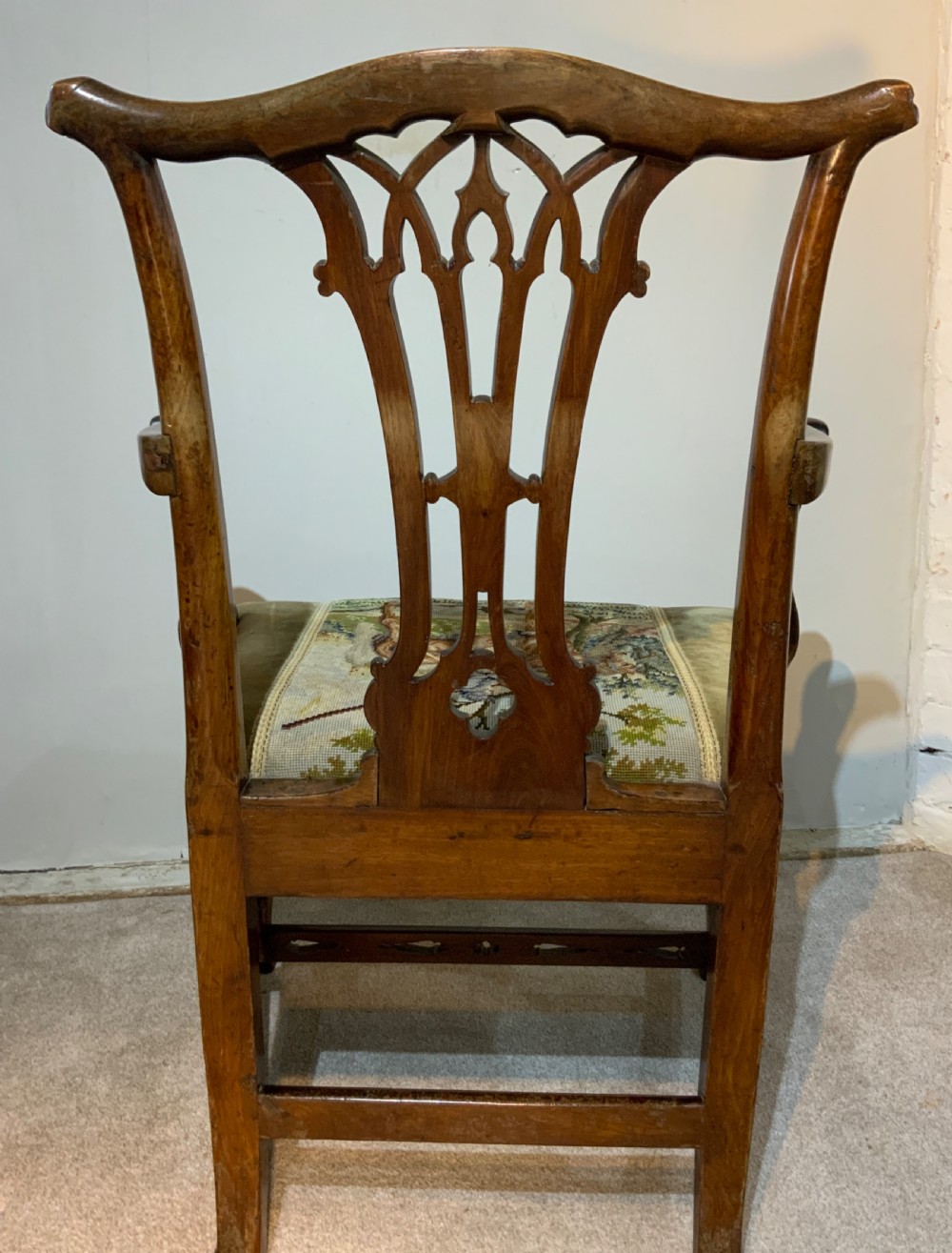 A Georgian dark mahogany armchair featuring an intricately carved pierced back splat, open curved arms, and a green velvet seat with an embroidered tapestry panel. View VI