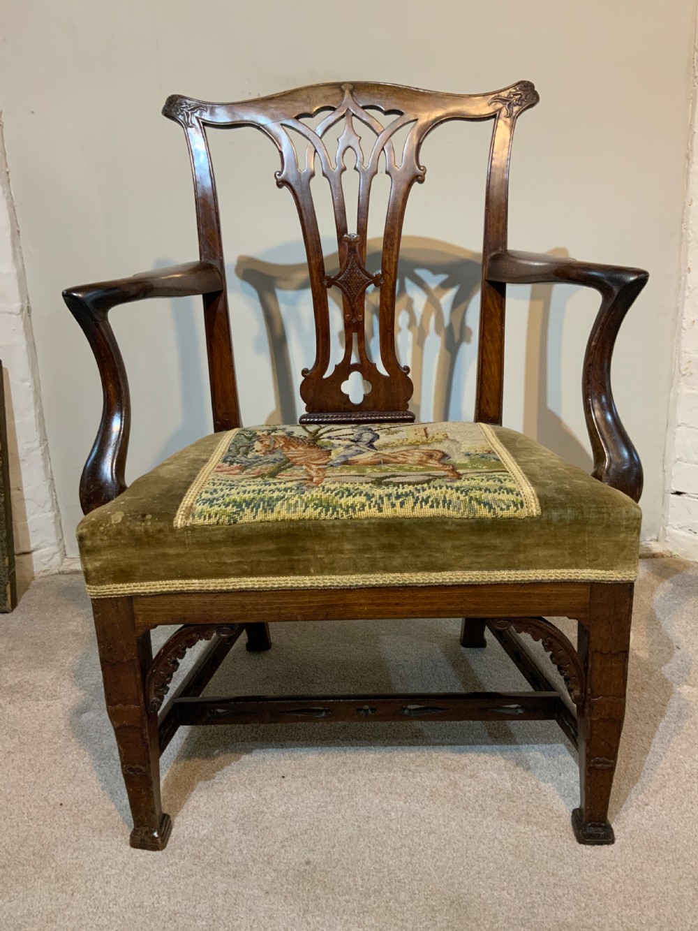 A Georgian dark mahogany armchair featuring an intricately carved pierced back splat, open curved arms, and a green velvet seat with an embroidered tapestry panel. View VIII