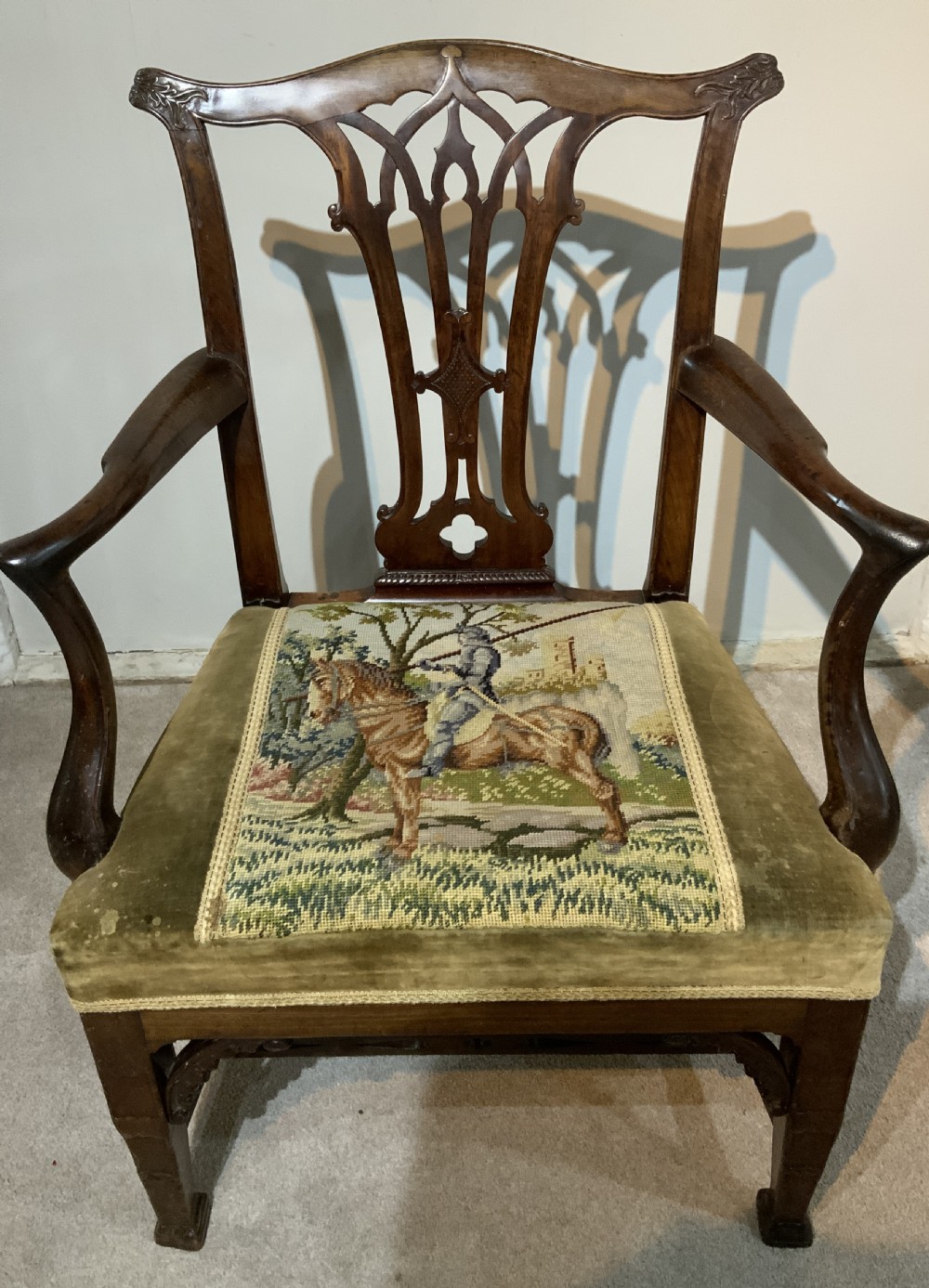 A Georgian dark mahogany armchair featuring an intricately carved pierced back splat, open curved arms, and a green velvet seat with an embroidered tapestry panel. View IX