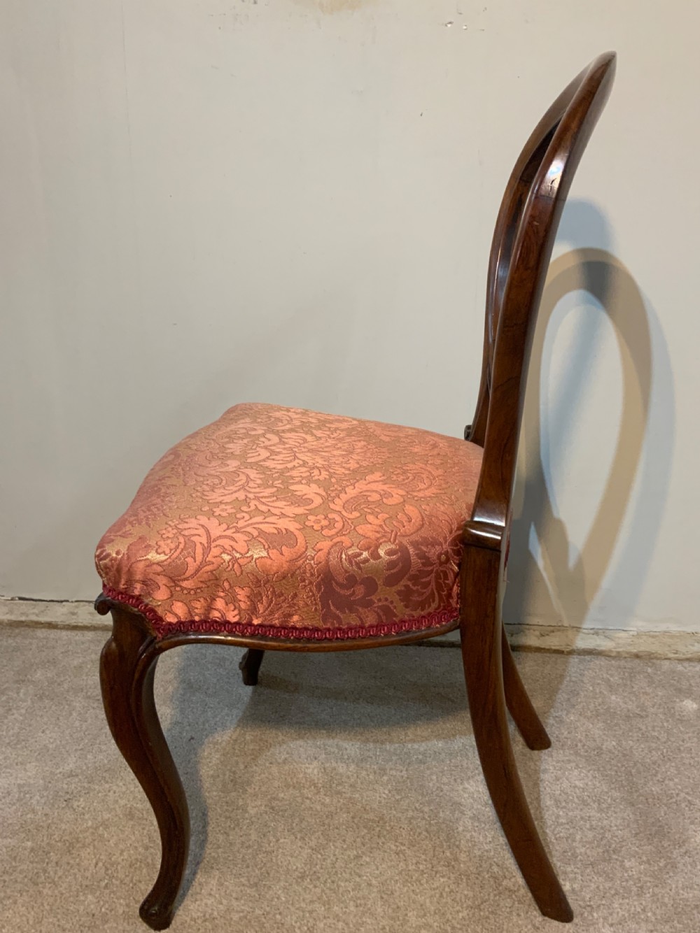 A set of six early Victorian rosewood balloon-back dining chairs with red damask upholstery and cabriole legs. View VI
