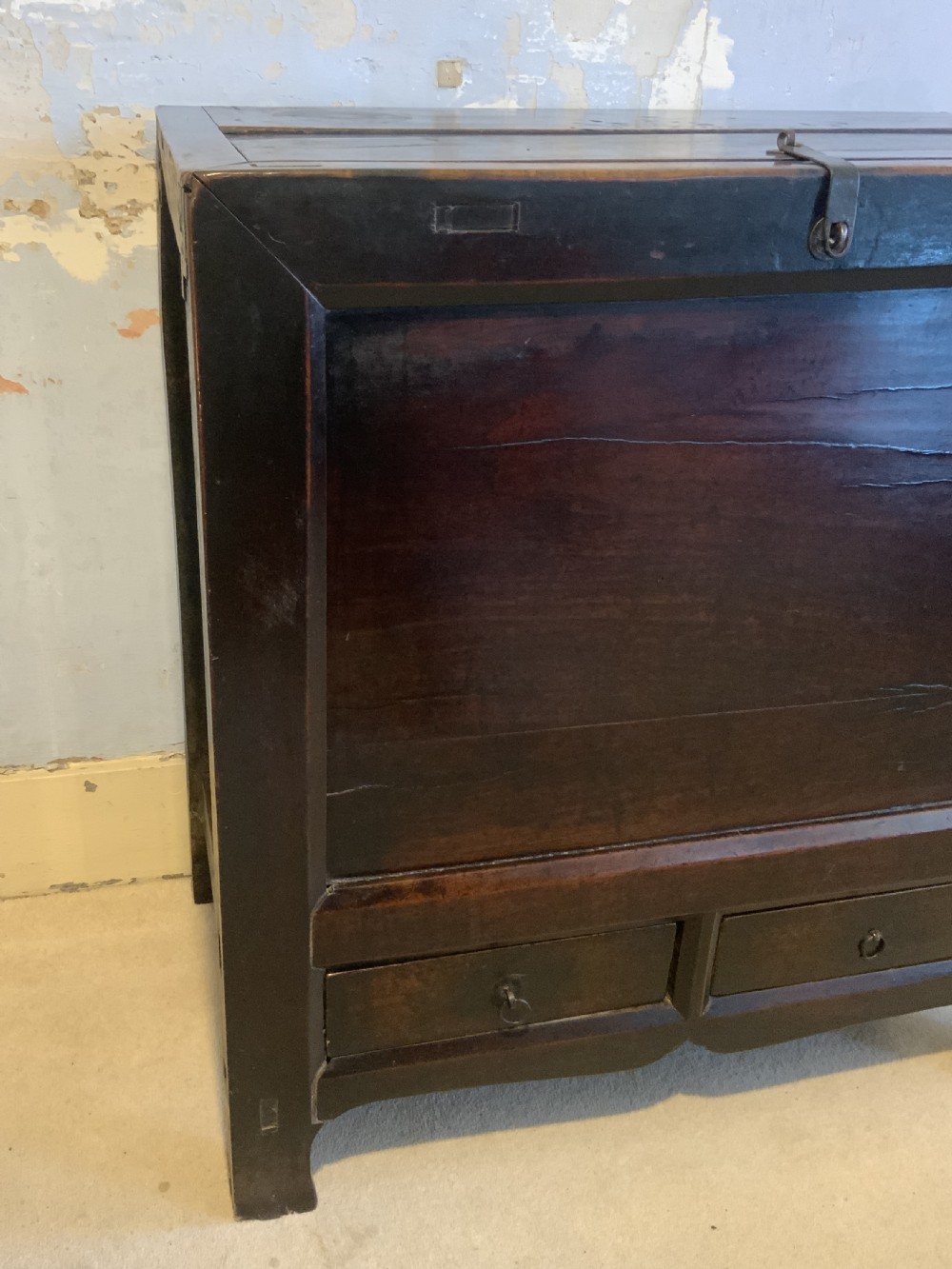 A dark brown 18th-century Chinese wooden chest featuring a top-opening lid, two lower drawers with metal ring handles, and iron latch hardware. View II