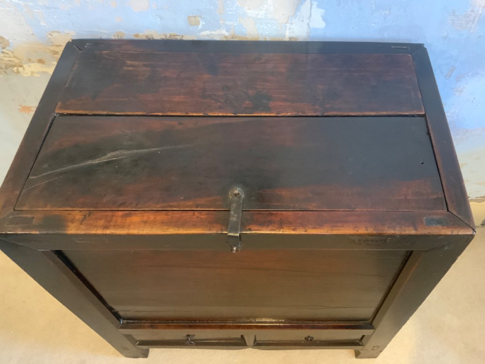 A dark brown 18th-century Chinese wooden chest featuring a top-opening lid, two lower drawers with metal ring handles, and iron latch hardware. View III