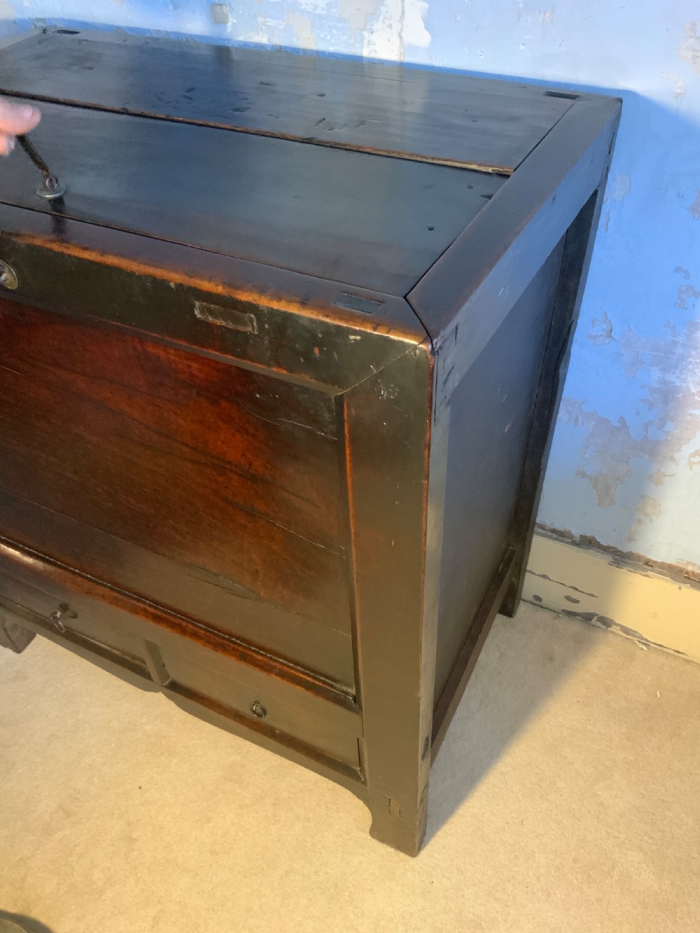 A dark brown 18th-century Chinese wooden chest featuring a top-opening lid, two lower drawers with metal ring handles, and iron latch hardware. View IV