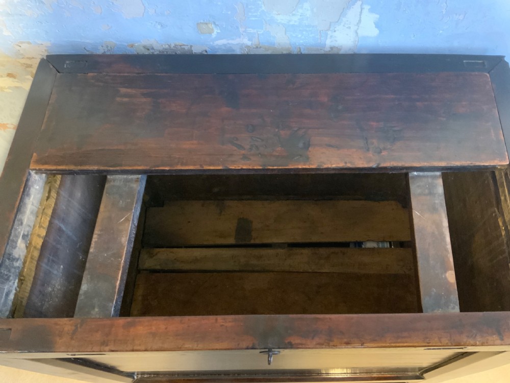 A dark brown 18th-century Chinese wooden chest featuring a top-opening lid, two lower drawers with metal ring handles, and iron latch hardware. View V