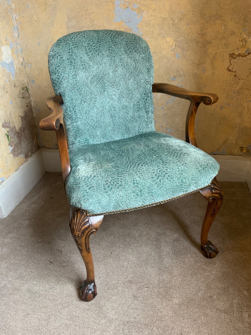 An antique walnut open armchair featuring light green textured upholstery, carved cabriole legs with ball and claw feet, and curved wooden armrests. View II