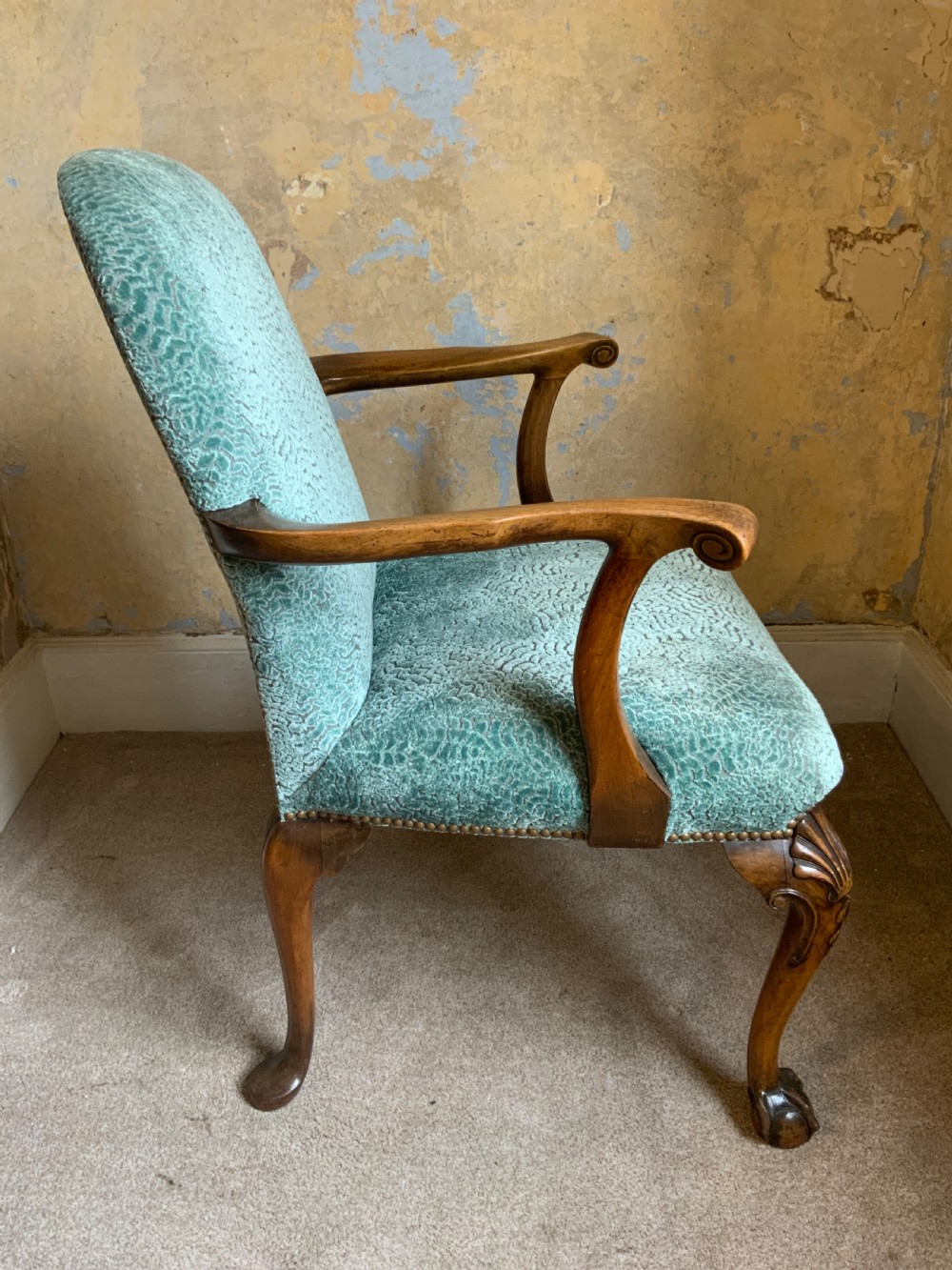 An antique walnut open armchair featuring light green textured upholstery, carved cabriole legs with ball and claw feet, and curved wooden armrests. View V