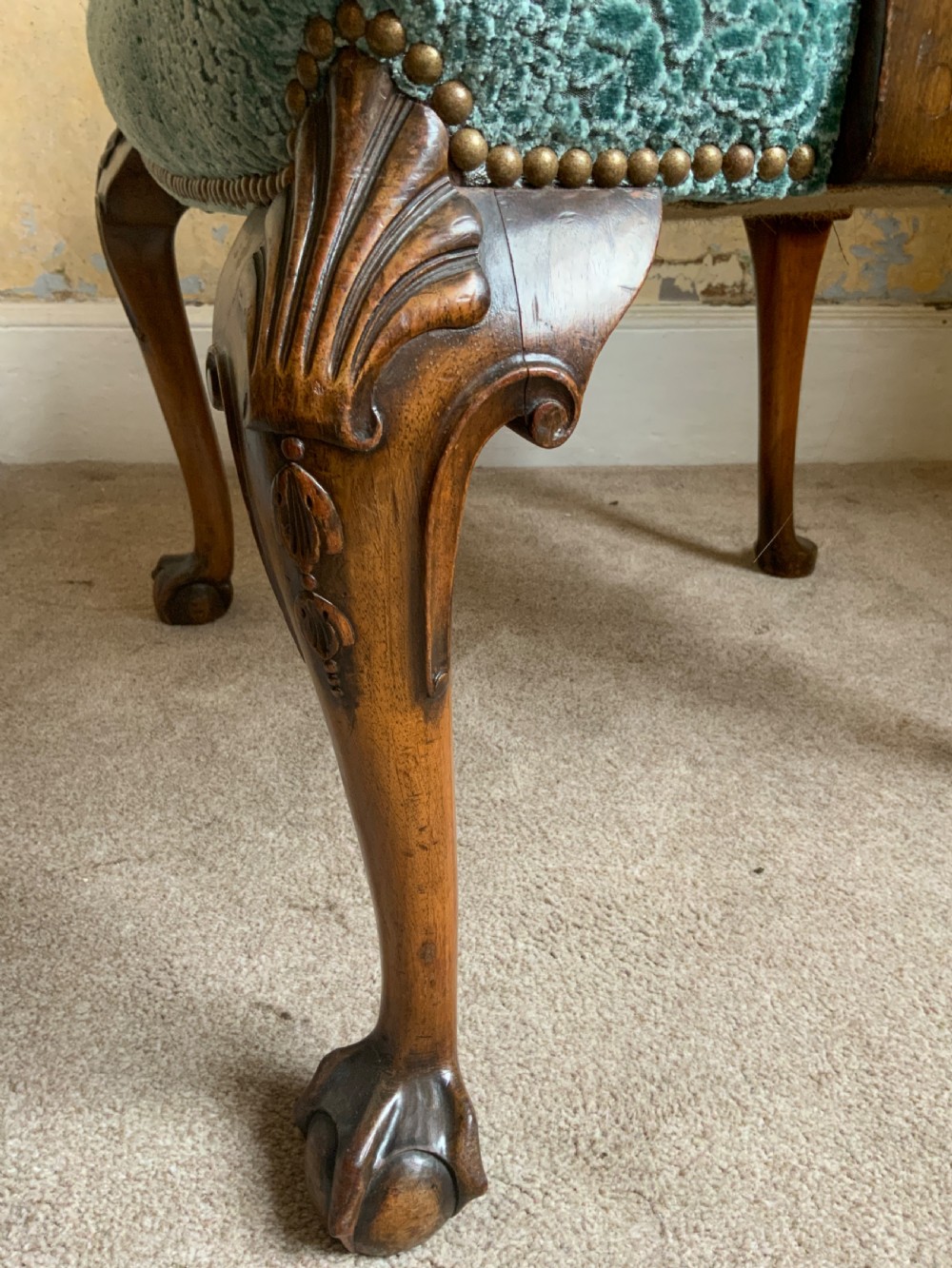An antique walnut open armchair featuring light green textured upholstery, carved cabriole legs with ball and claw feet, and curved wooden armrests. View VI