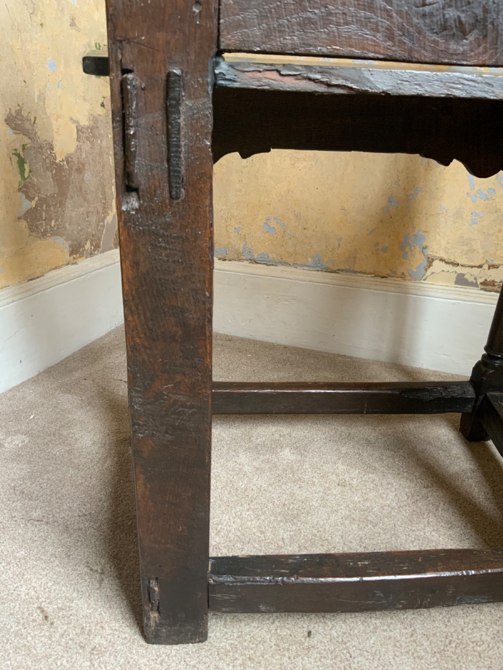 A dark oak 17th-century wainscot armchair featuring a high carved back panel with botanical motifs, turned front legs, and turned crest finials. View VII