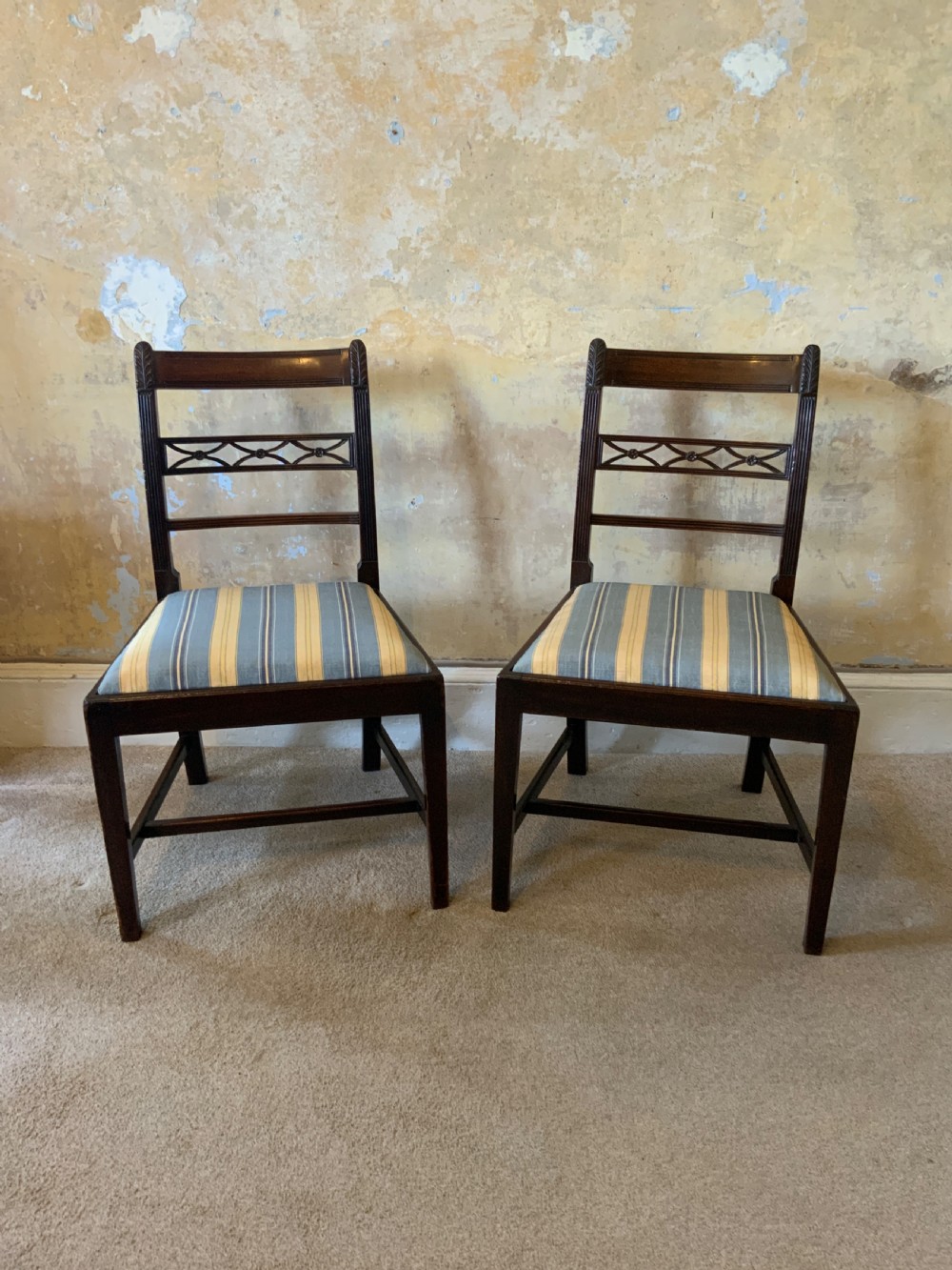A set of six dark brown mahogany dining chairs featuring open ladder-backs with carved detailing and blue-and-yellow striped upholstered drop-in seats. View II