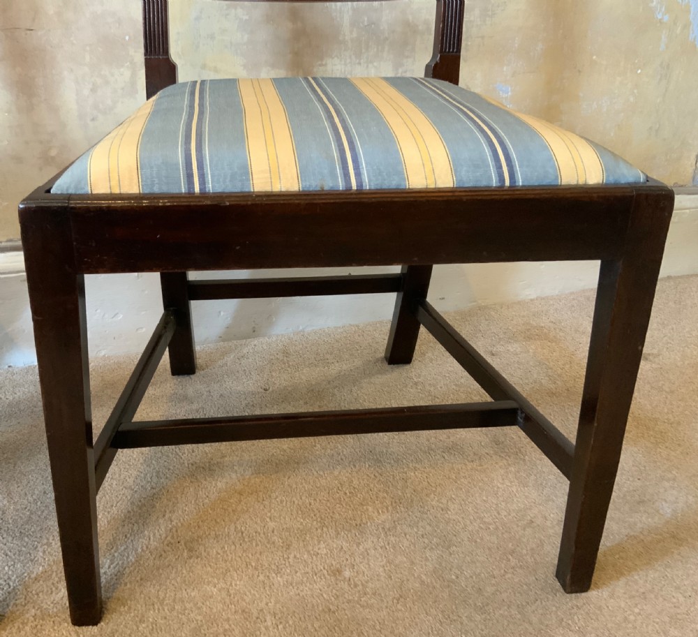 A set of six dark brown mahogany dining chairs featuring open ladder-backs with carved detailing and blue-and-yellow striped upholstered drop-in seats. View IV
