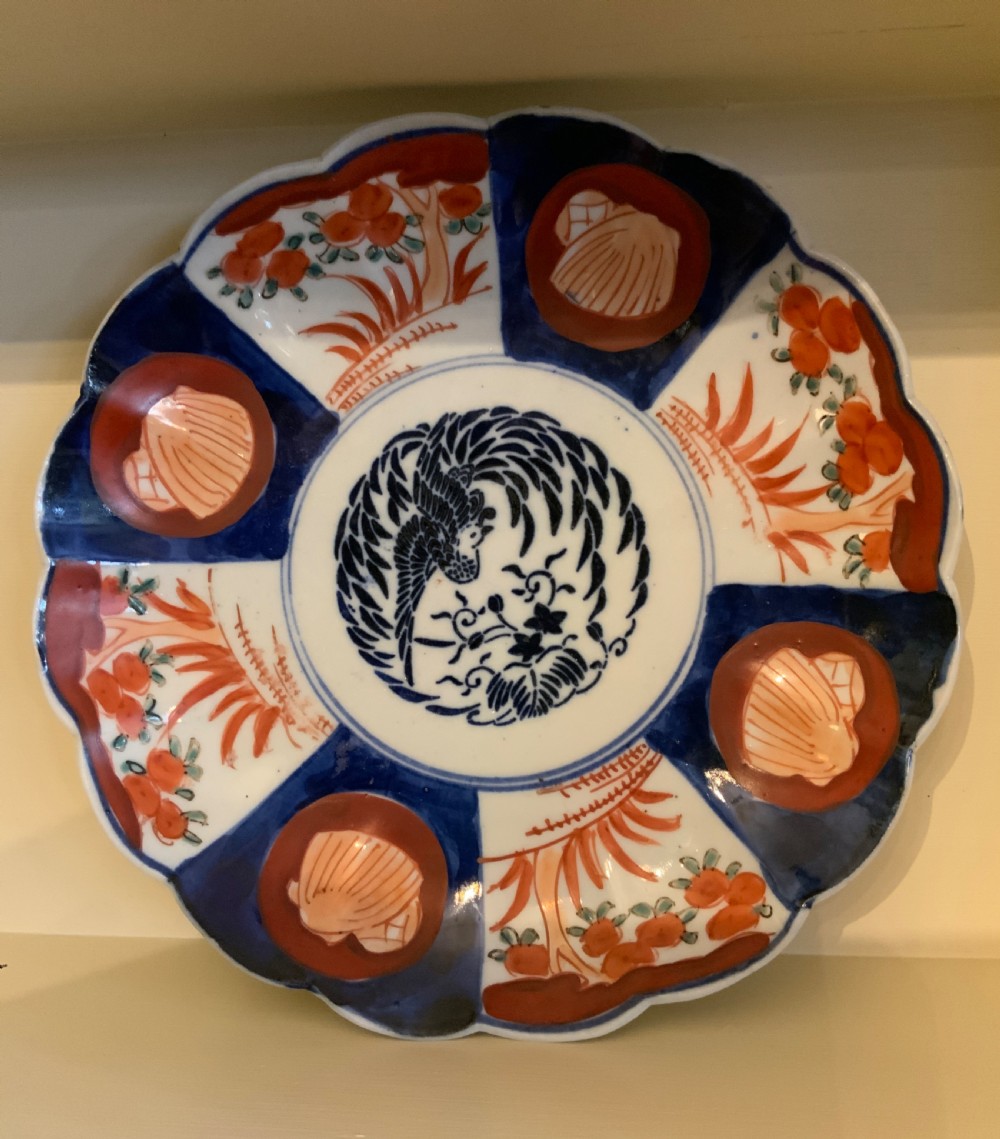 A set of four 19th-century Japanese Imari porcelain plates featuring scalloped rims and detailed cobalt blue and iron-red floral panelling. View IV