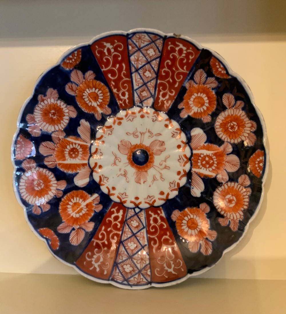 A set of four 19th-century Japanese Imari porcelain plates featuring scalloped rims and detailed cobalt blue and iron-red floral panelling. View VI