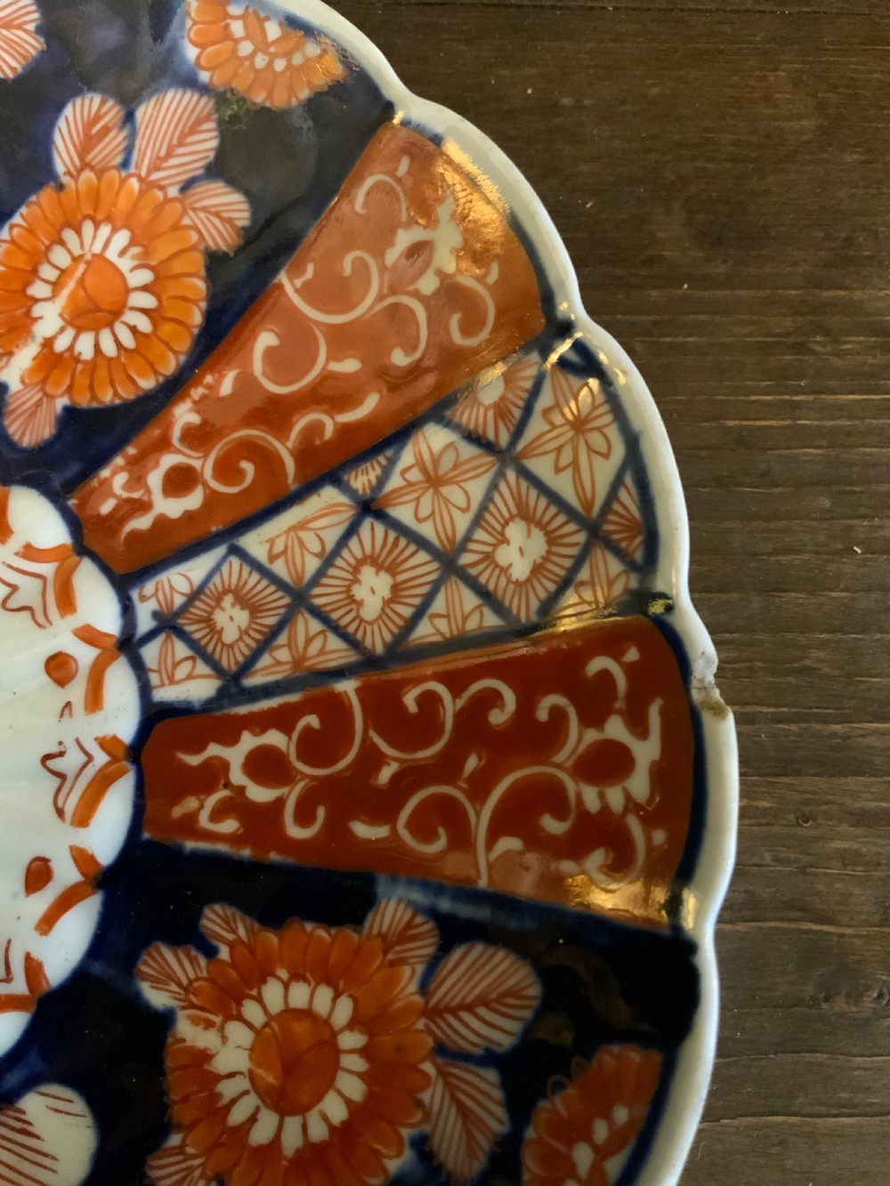 A set of four 19th-century Japanese Imari porcelain plates featuring scalloped rims and detailed cobalt blue and iron-red floral panelling. View X