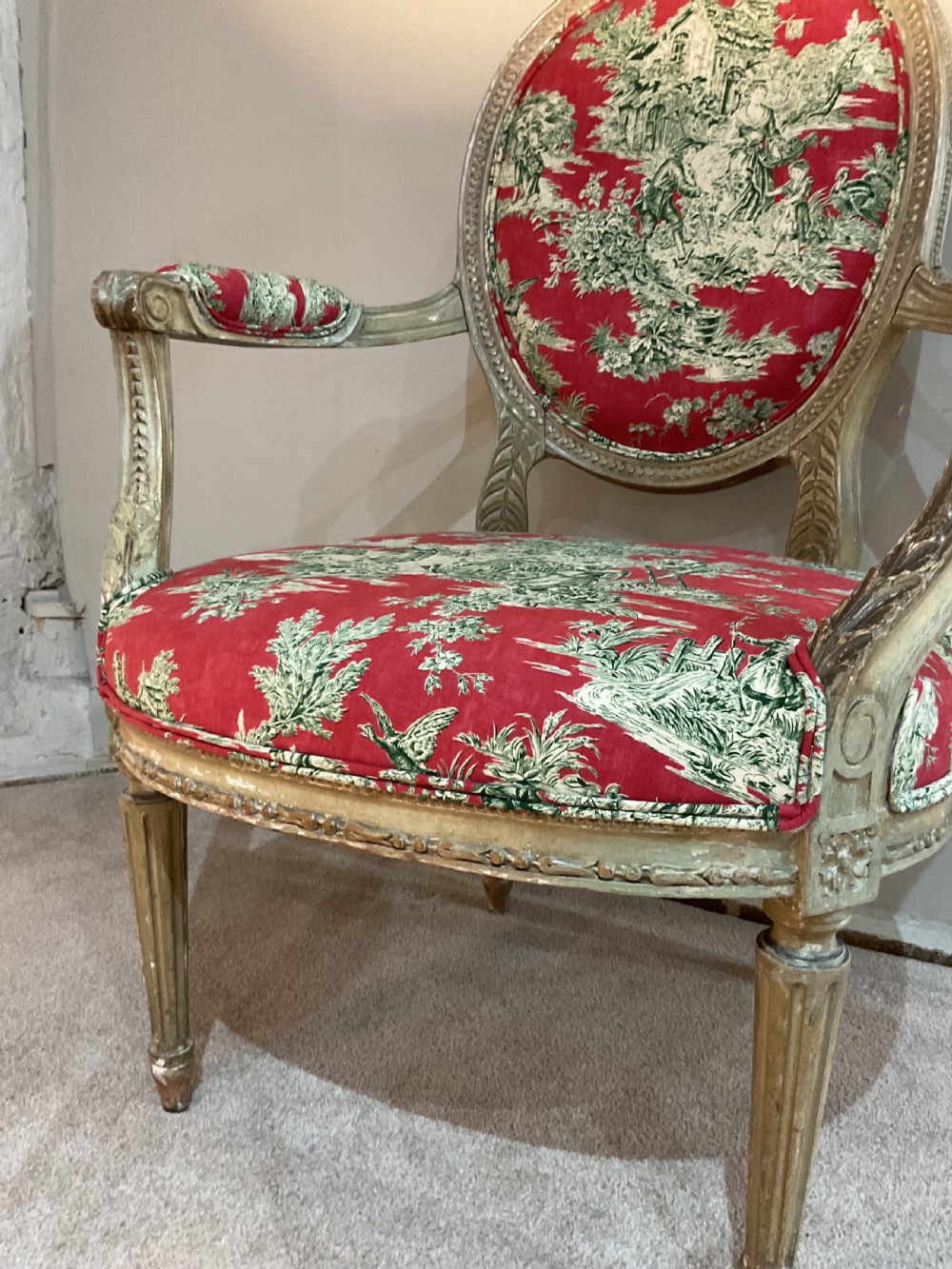 A pair of 18th-century French Louis XVI open armchairs featuring oval backrests, carved fluted legs, distressed gilding, and red patterned textile upholstery. View II