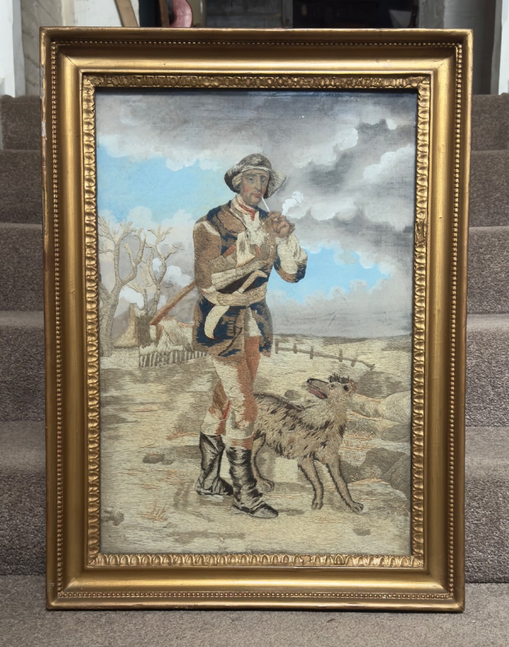 An antique late Regency long stitch silk embroidery depicting a country huntsman with his dog, framed in an ornate giltwood frame. View IV