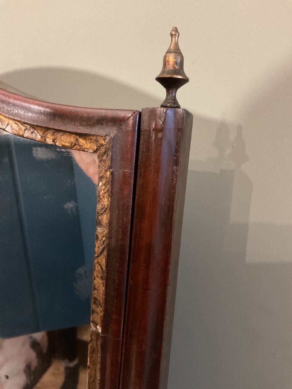 A George II period dark walnut toilet mirror featuring an arched adjustable swing frame set above a shaped three-drawer base with brass handles. View IV
