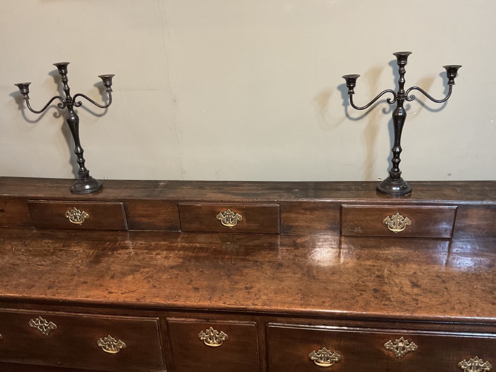 An 18th-century dark oak dresser base featuring brass hardware, three main drawers beneath three smaller upper drawers, a scalloped apron, and front cabriole legs. View III