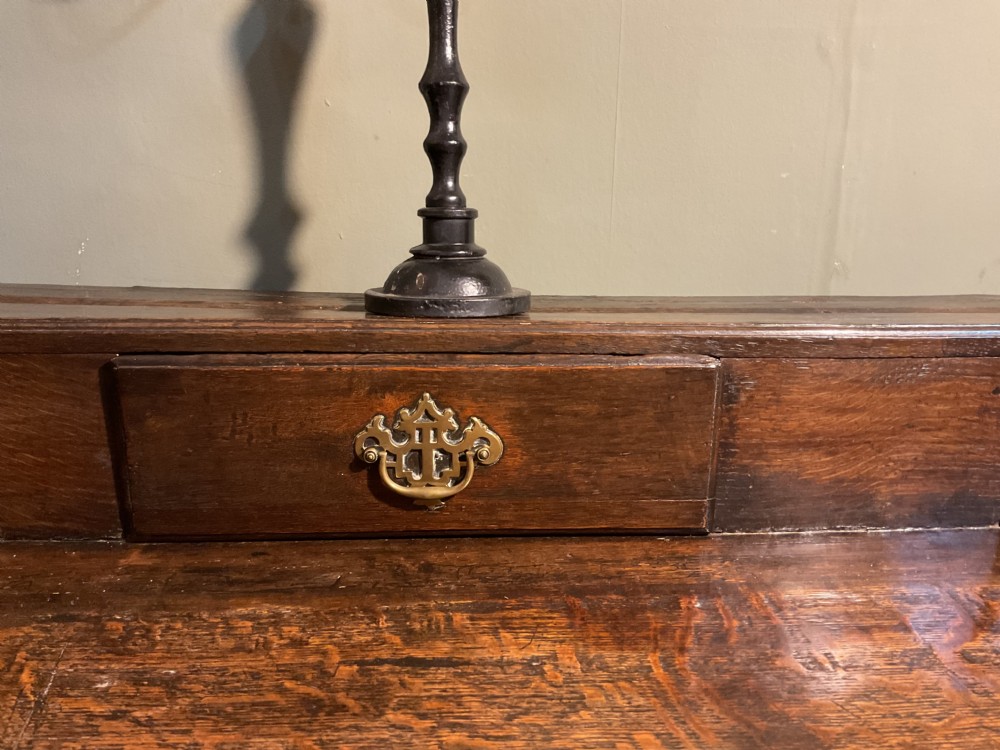 An 18th-century dark oak dresser base featuring brass hardware, three main drawers beneath three smaller upper drawers, a scalloped apron, and front cabriole legs. View IV