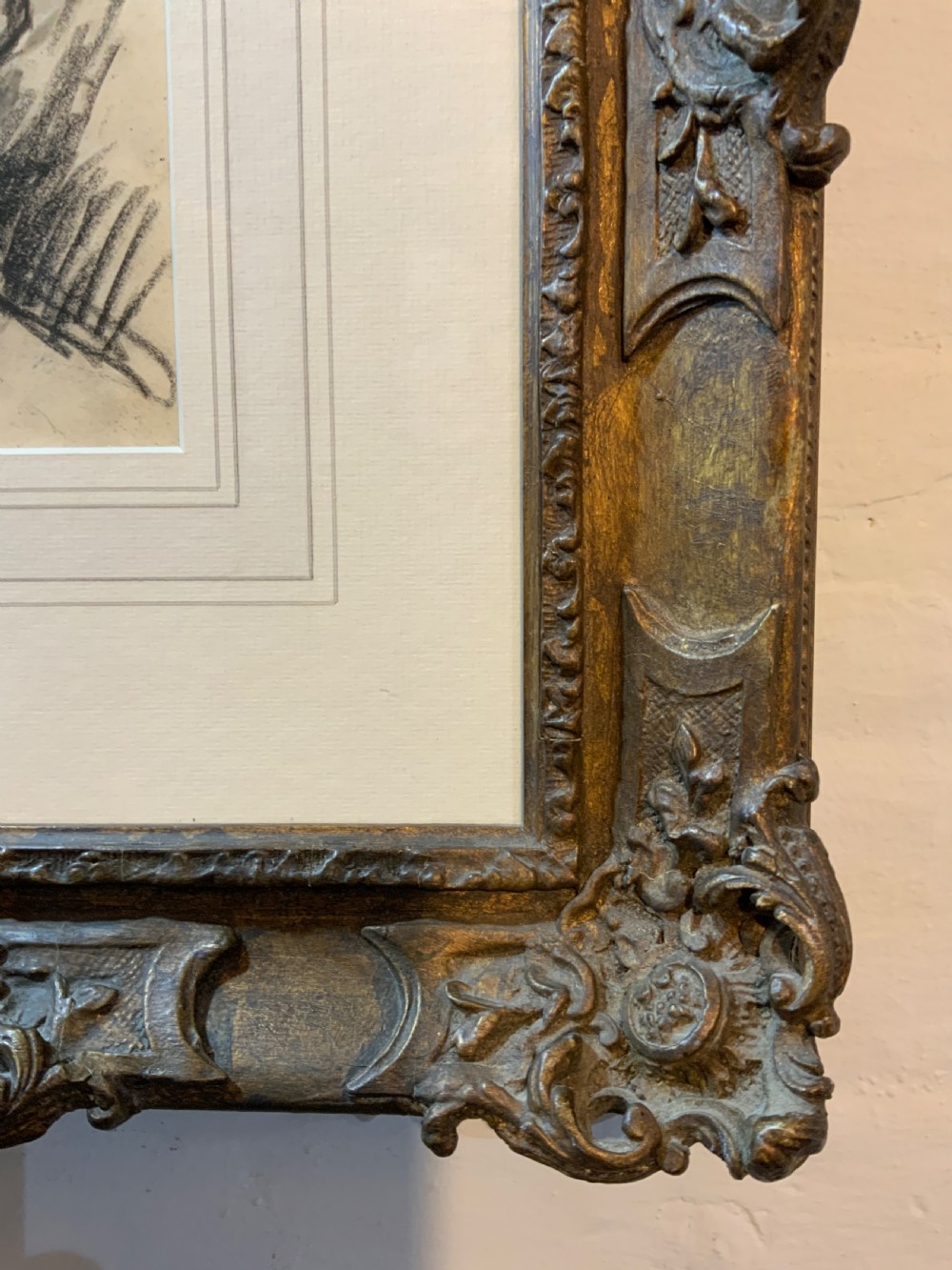 A framed charcoal portrait drawing of a woman wearing a hat, mounted inside an ornate carved gilt frame. View II