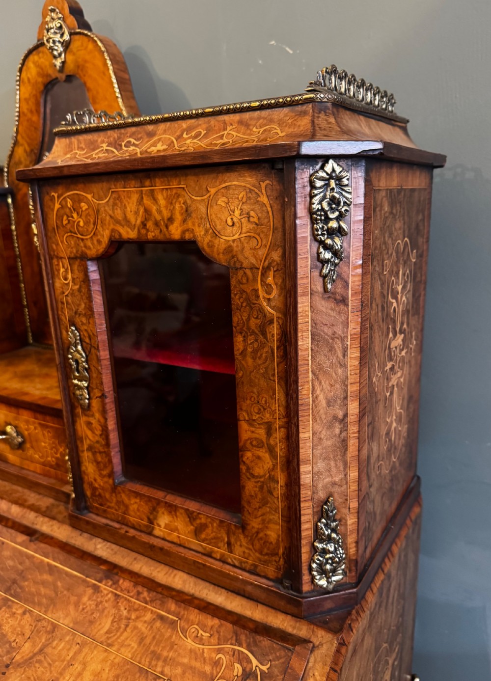 A burr walnut bonheur du jour writing desk featuring floral marquetry, cabriole legs with gilt bronze mounts, and an upper section with twin glazed cabinets framing a central mirror. View II