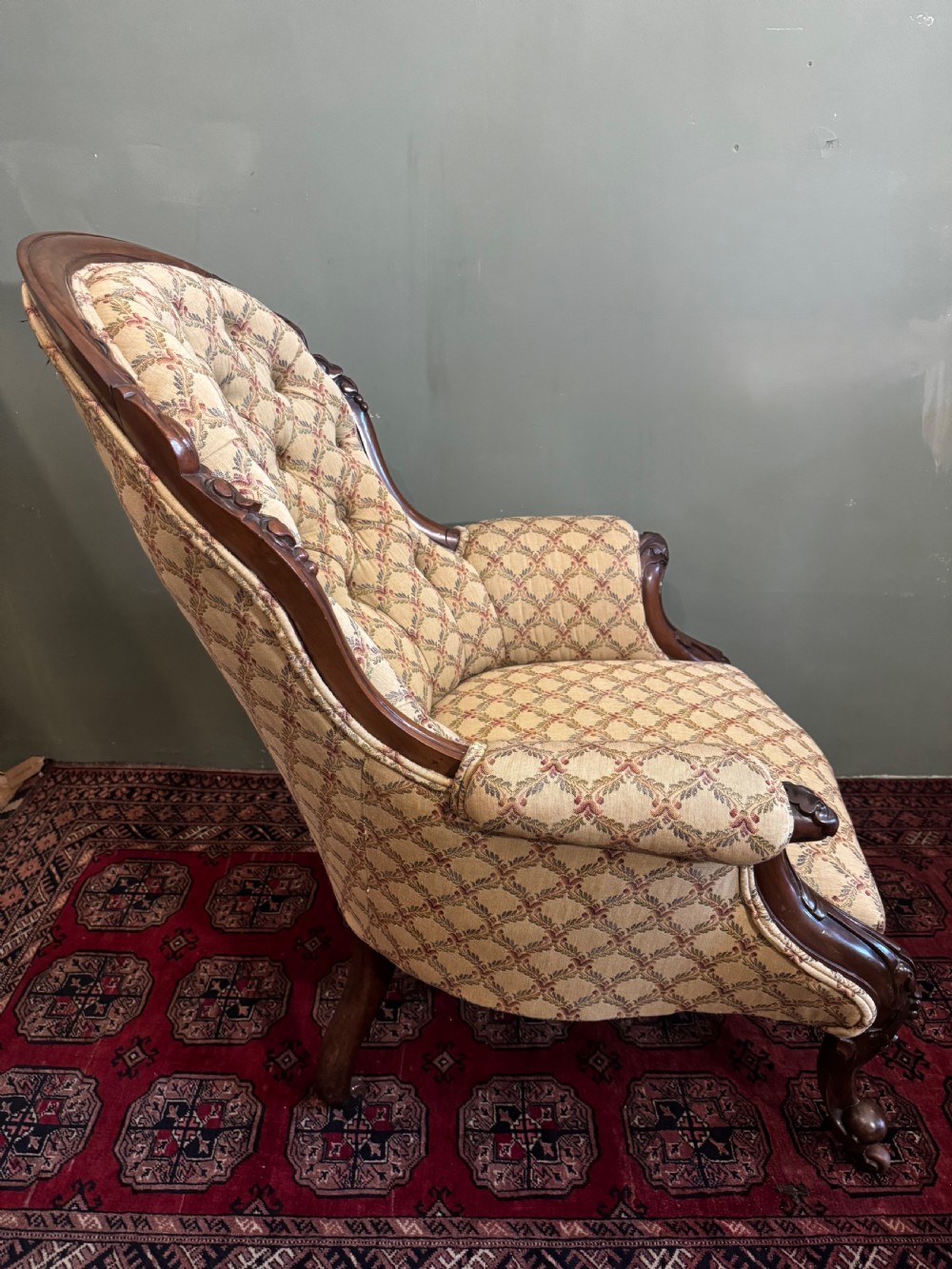 A Victorian mahogany armchair with patterned button-backed upholstery, carved wooden frame, and front cabriole legs. View II