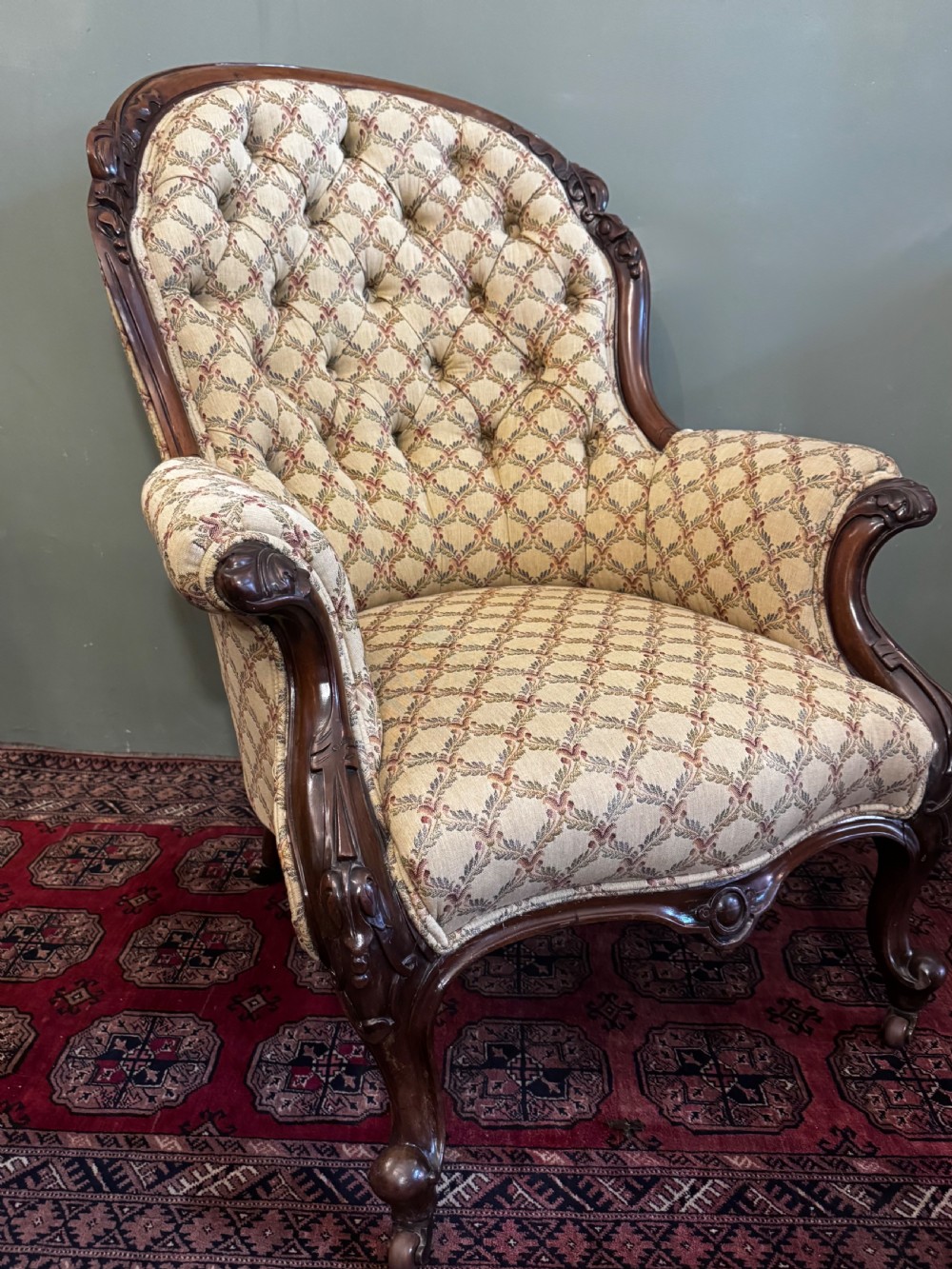 A Victorian mahogany armchair with patterned button-backed upholstery, carved wooden frame, and front cabriole legs. View III
