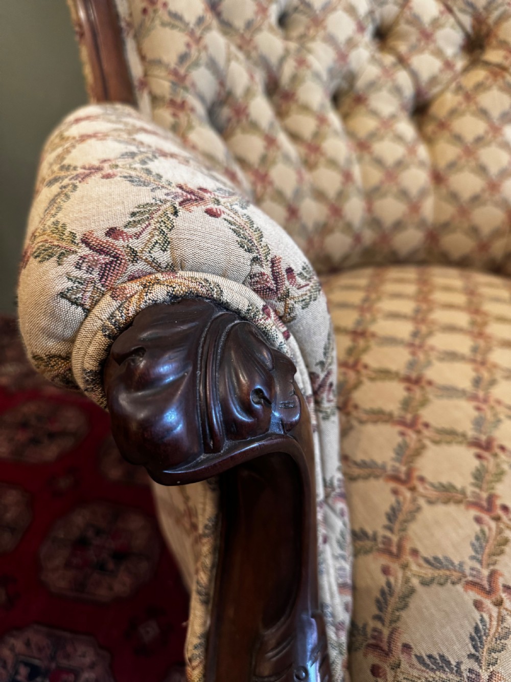 A Victorian mahogany armchair with patterned button-backed upholstery, carved wooden frame, and front cabriole legs. View IV