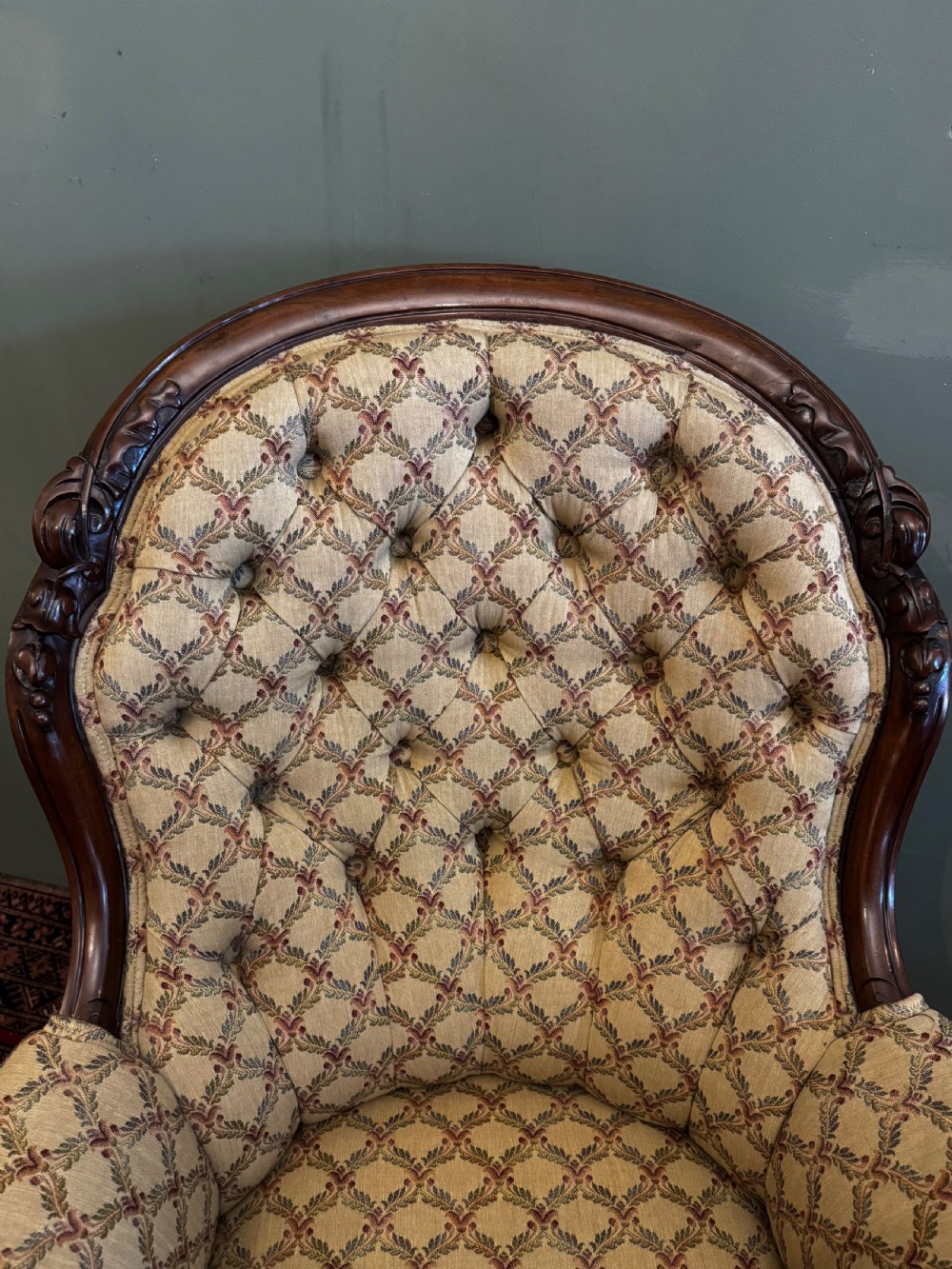 A Victorian mahogany armchair with patterned button-backed upholstery, carved wooden frame, and front cabriole legs. View VI