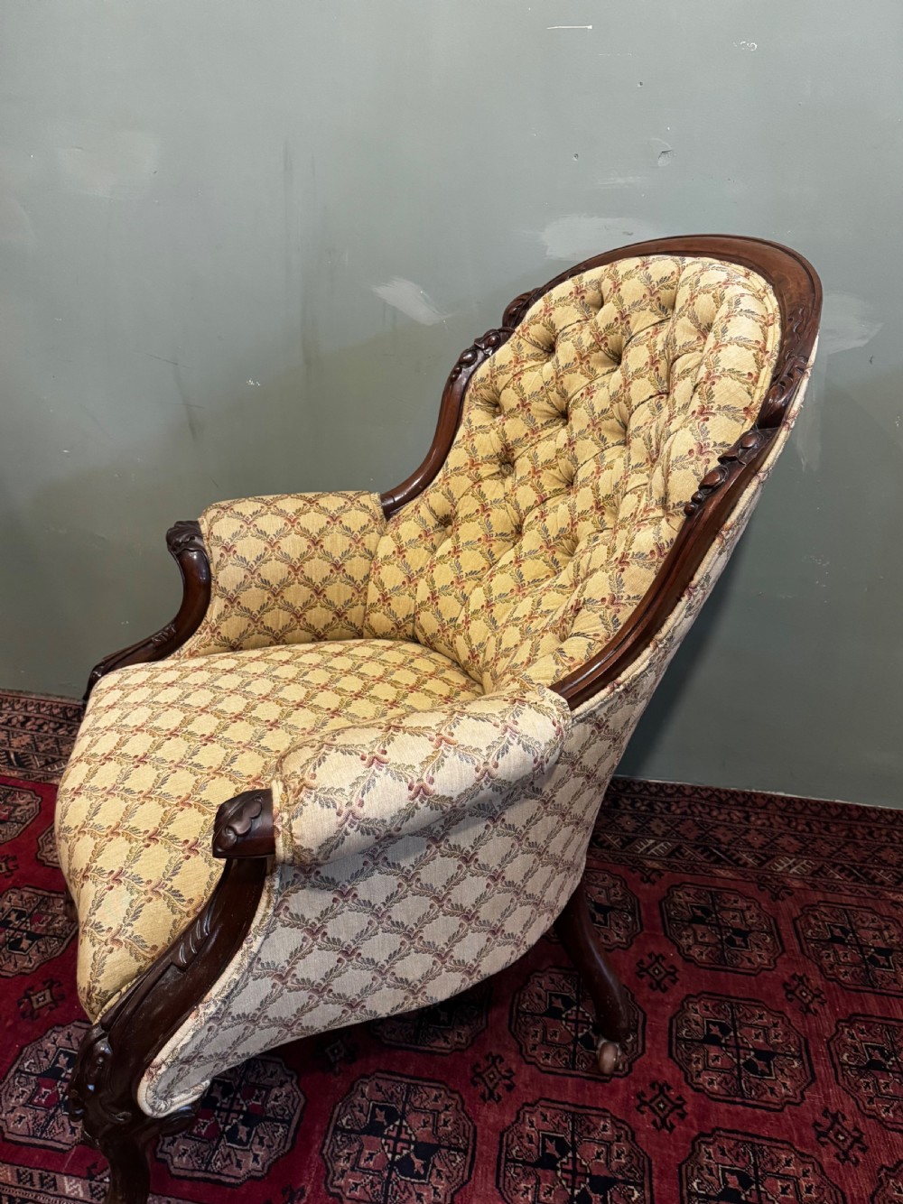 A Victorian mahogany armchair with patterned button-backed upholstery, carved wooden frame, and front cabriole legs. View XI